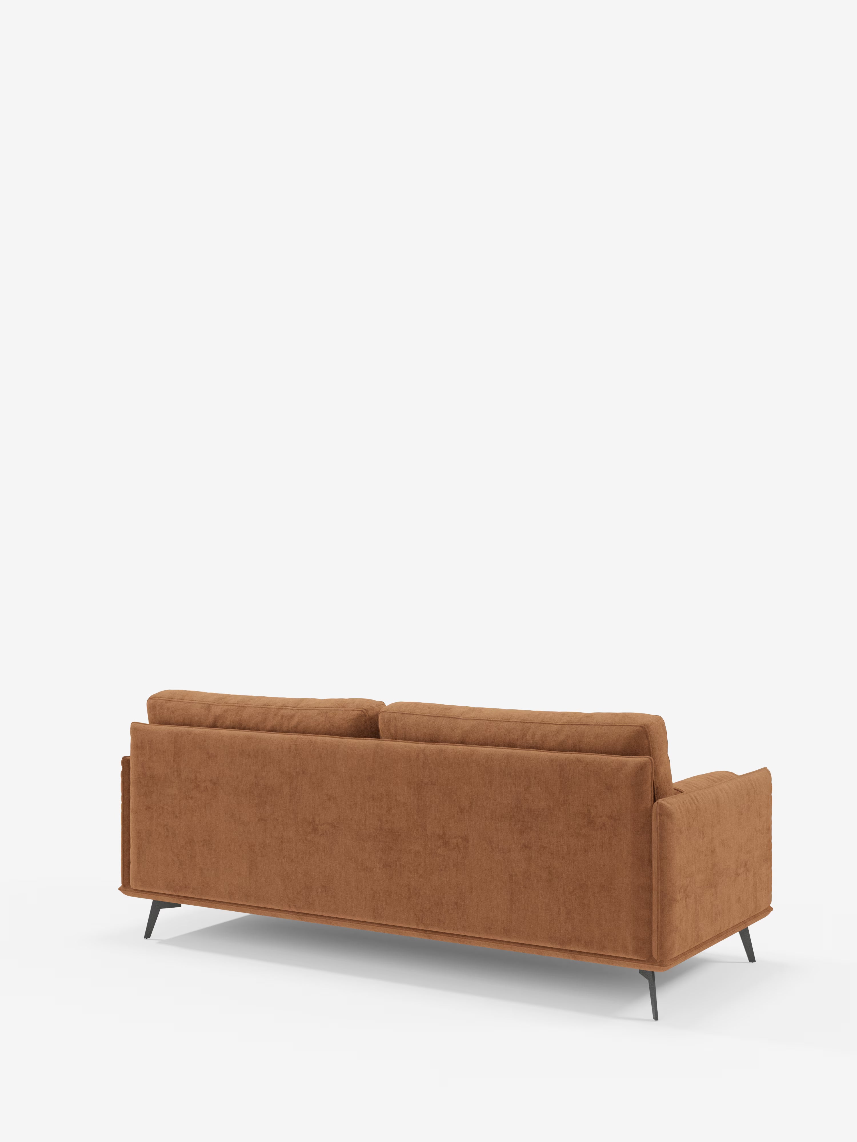 La linea Basalto Divano lineare a 2 o 3 posti di Divani.Store presenta un design moderno in stile mid-century con rivestimento T31 color ruggine e smacchiabile, braccioli dritti, cuscini dello schienale trapuntati e base angolare in metallo nero. È raffigurato di retro su uno sfondo bianco a tinta unita.