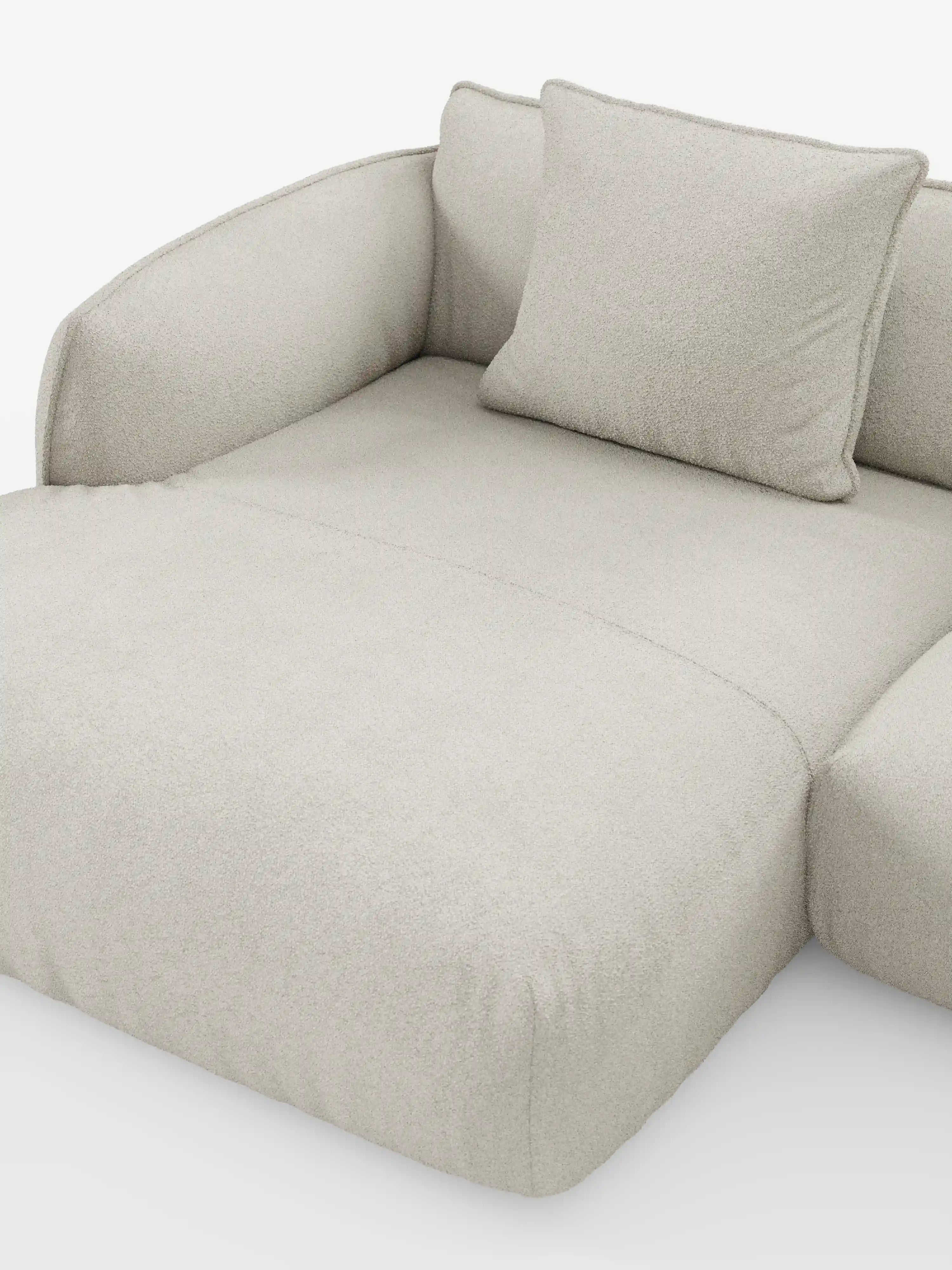 Un divano angolare panoramico componibile moderno e minimalista, di colore beige, con penisola e angolo: il modello Nimbus di Divani.Store, è esposto su uno sfondo bianco. Realizzato in Italia, questo elegante divano presenta braccioli ricurvi, un unico cuscino quadrato abbinato e un morbido tessuto T33 smacchiabile dalla trama soffice, che gli conferisce un aspetto lussuoso e confortevole.
