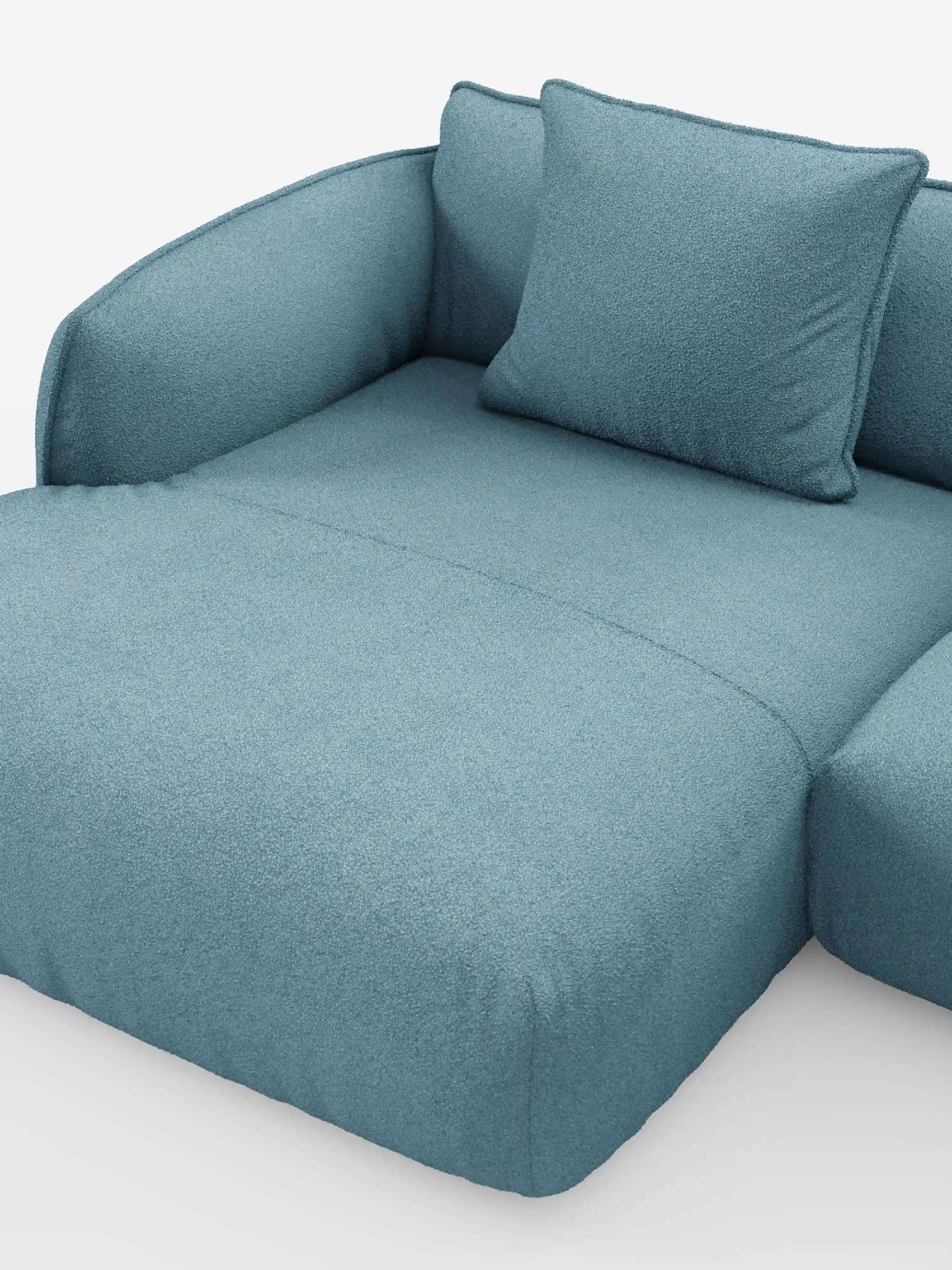 Il divano angolare panoramico componibile Nimbus, modello T33 di Divani.Store, è presentato in un tessuto azzurro leggermente testurizzato, con braccioli morbidi e arrotondati e un cuscino quadrato abbinato. Il divano letto è raffigurato in posizione distesa, con lo sfondo bianco.