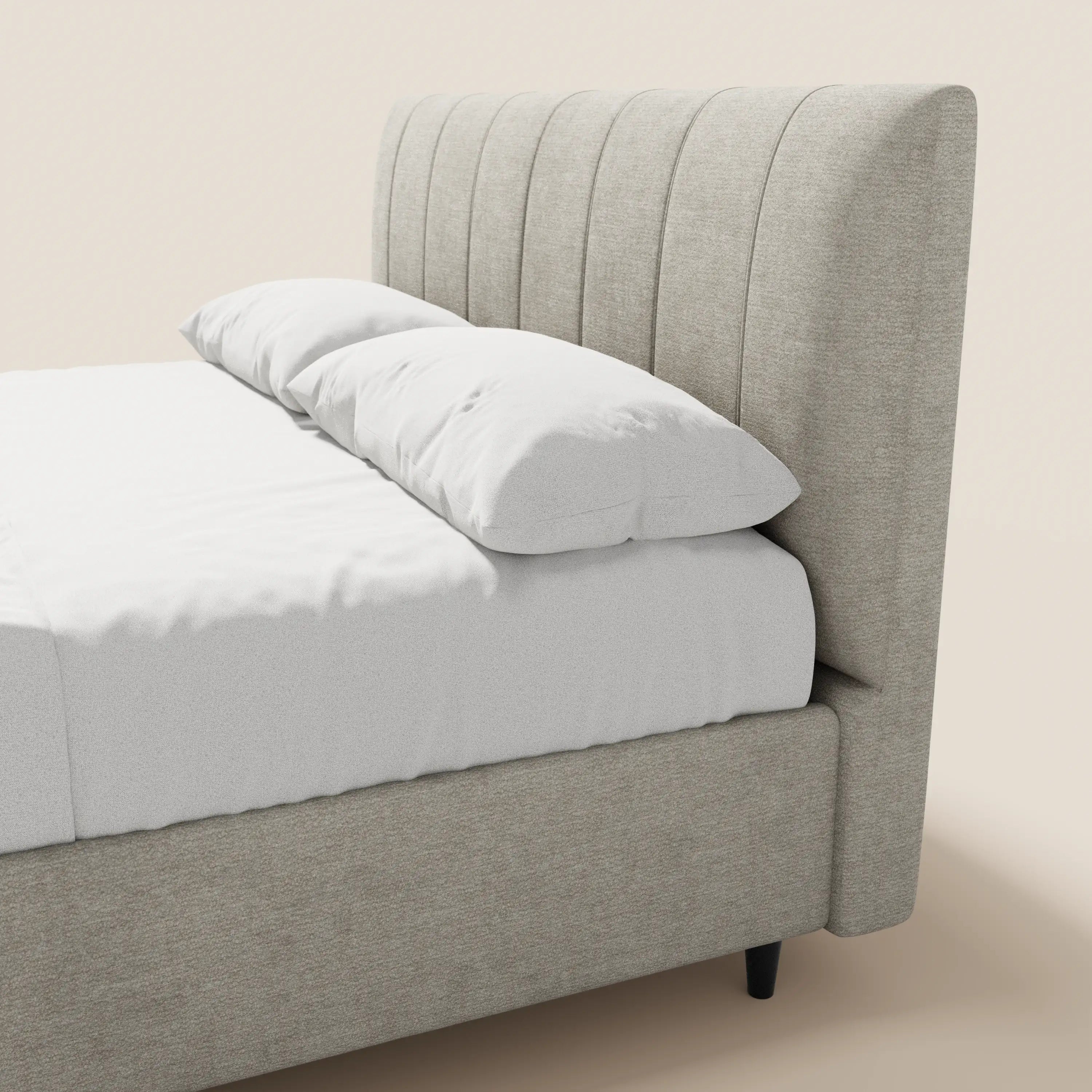 Il letto imbottito ONYX con contenitore di Letti.store presenta una testiera alta con scanalature verticali in tessuto certificato Oeko-Tex® color beige chiaro, linee pulite ed è abbinato a cuscini e biancheria da letto bianchi su uno sfondo neutro.