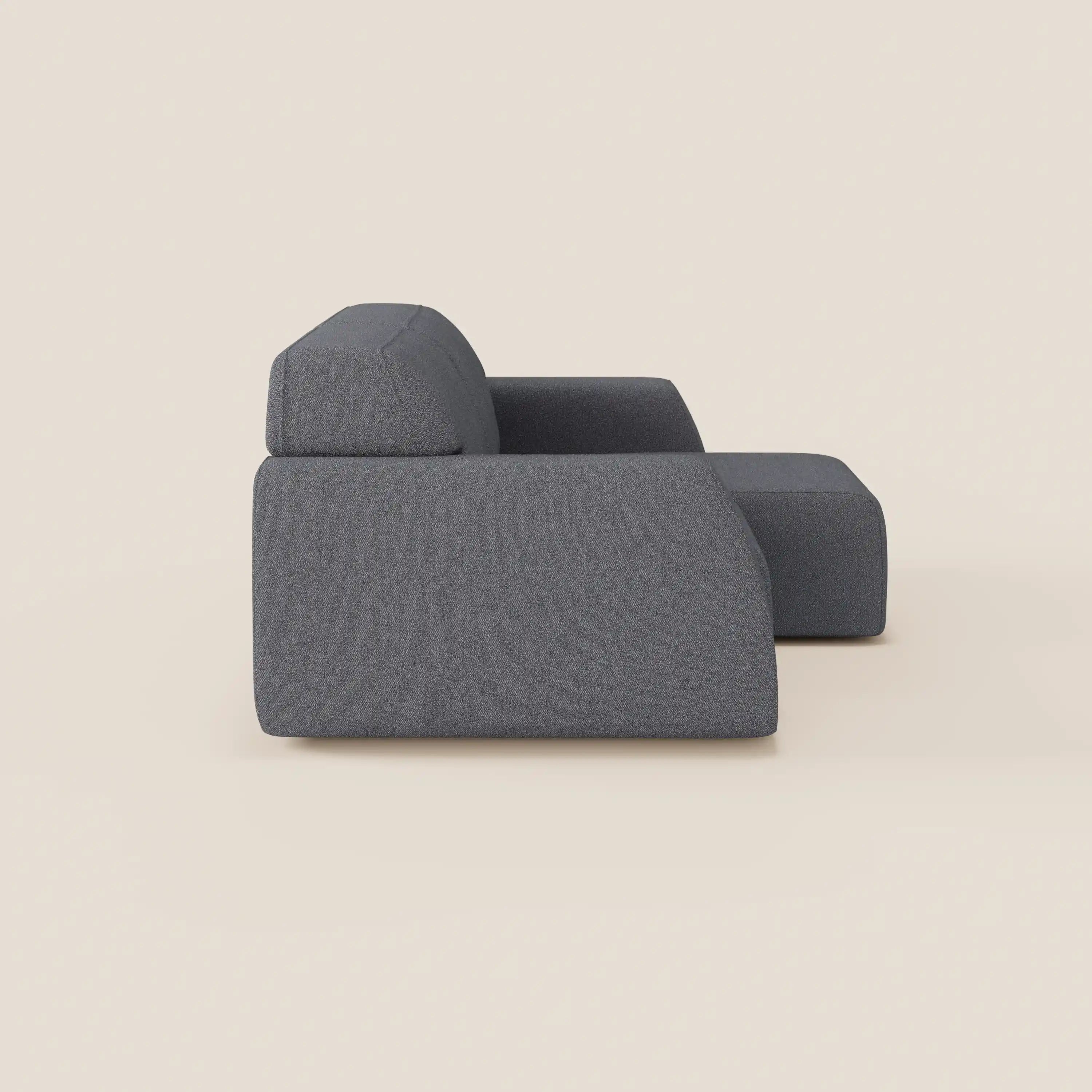 Il divano Orbit 2 e 3 posti di Divani.Store, in tessuto smacchiabile effetto cotone T33, con bracciolo destro e pouf coordinato, sfoggia linee pulite e forme squadrate su sfondo beige; visibile solo il lato sinistro.
