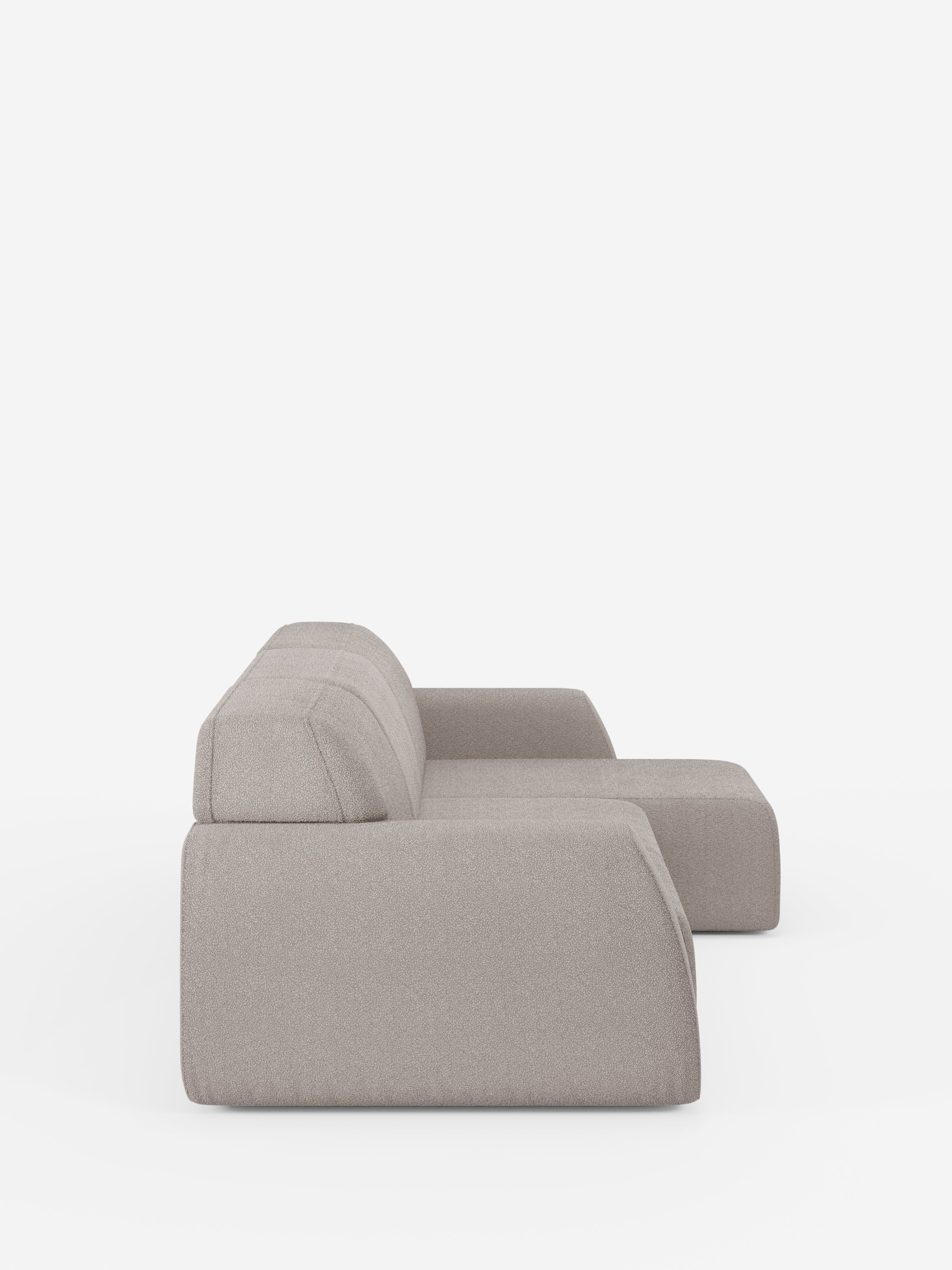 Una vista laterale del divano angolare Orbit con penisola reversibile e tutte le sedute allungabili in tessuto smacchiabile effetto cotone T33 di Divani.Store, caratterizzato da un design moderno in grigio chiaro con linee pulite e cuscini dal profilo basso, su uno sfondo bianco a tinta unita. Questo divano morbido e confortevole è privo di gambe a vista, il che ne esalta l’aspetto minimalista.