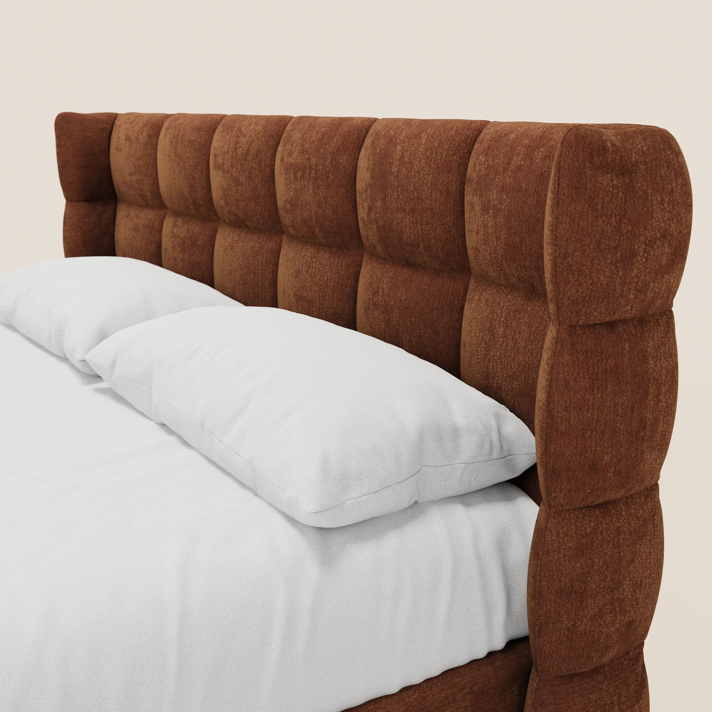 Un primo piano del letto imbottito RAGNAR con contenitore e testiera capitonné avvolgente di Letti.store, in tessuto marrone certificato Oeko-Tex®, presentato con cura con biancheria da letto e cuscini bianchi su uno sfondo chiaro e uniforme.