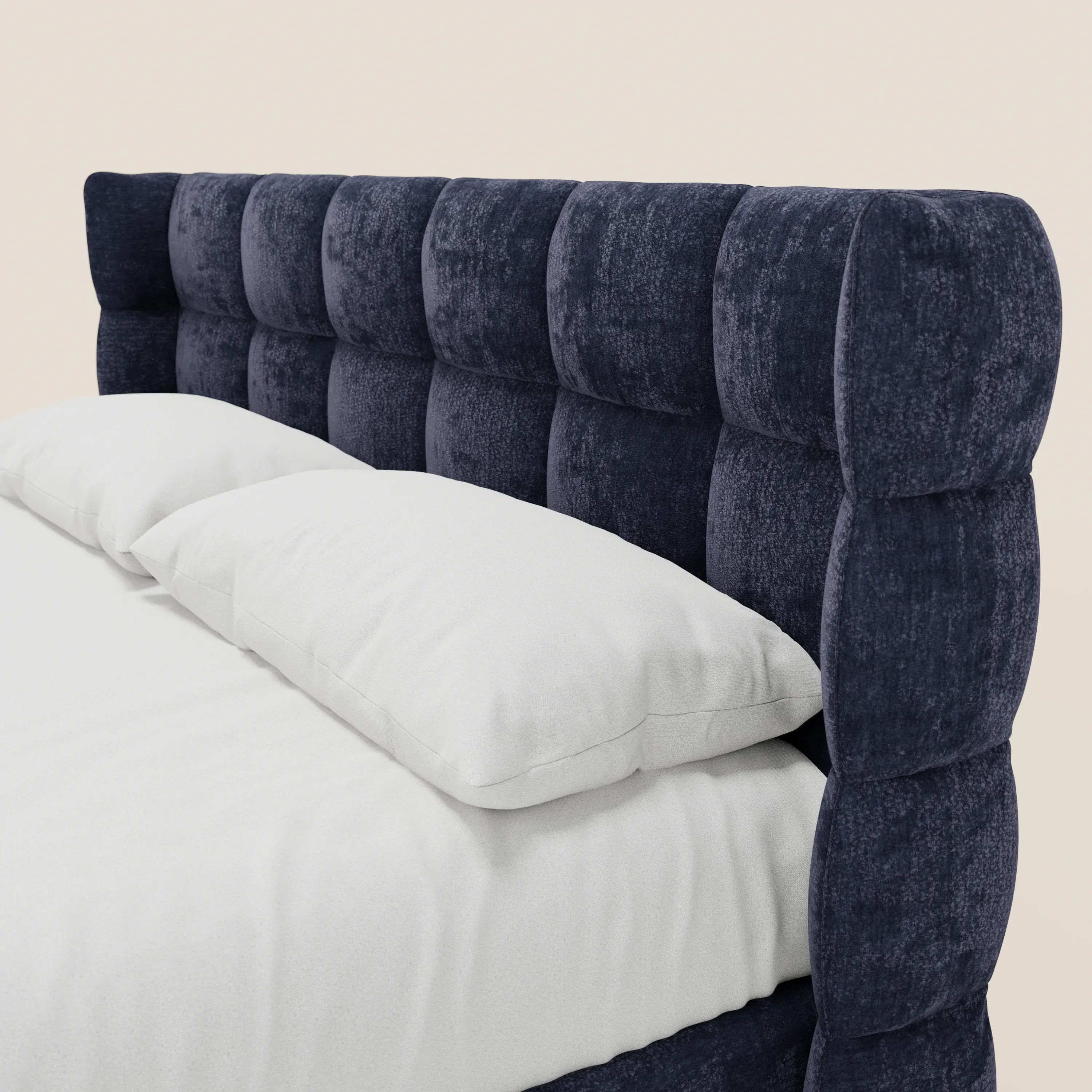Un primo piano del letto imbottito RAGNAR di Letti.store, caratterizzato da una testiera in velluto blu navy scuro con lavorazione capitonné a motivo a griglia e da una base contenitiva. Il letto è rivestito con biancheria da letto e cuscini bianchi, su uno sfondo chiaro. Tessuto certificato Oeko-Tex®.