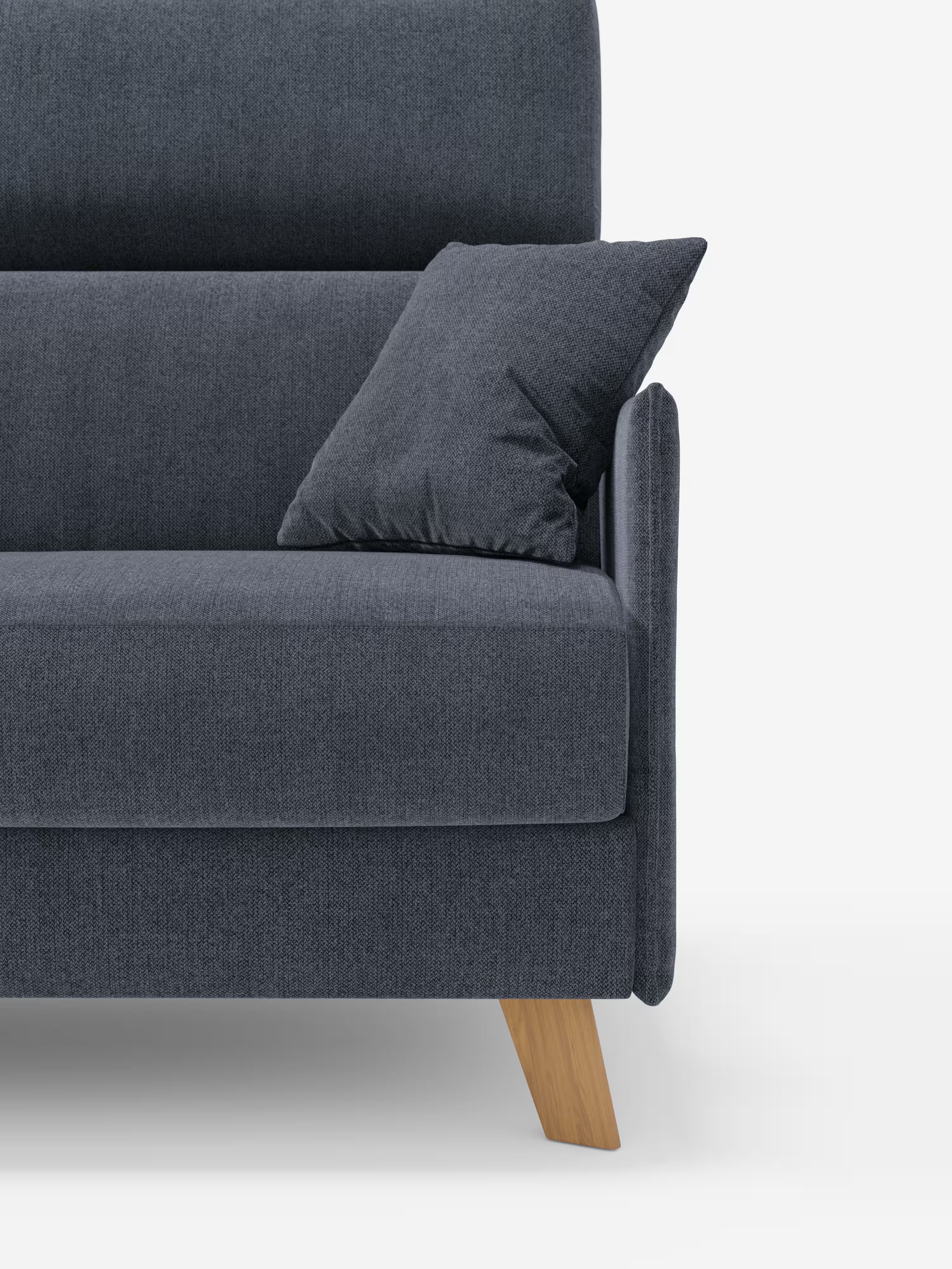 Primo piano del divano letto matrimoniale Sole di Divani.Store, caratterizzato da un moderno rivestimento in tessuto T23 grigio scuro smacchiabile e da un cuscino coordinato. Questo modello compatto si distingue per le linee pulite, i morbidi rivestimenti rimovibili al 100%, le gambe angolate in legno chiaro e i poggiatesta regolabili. Sullo sfondo bianco a tinta unita, lo stile minimalista e contemporaneo risalta magnificamente.