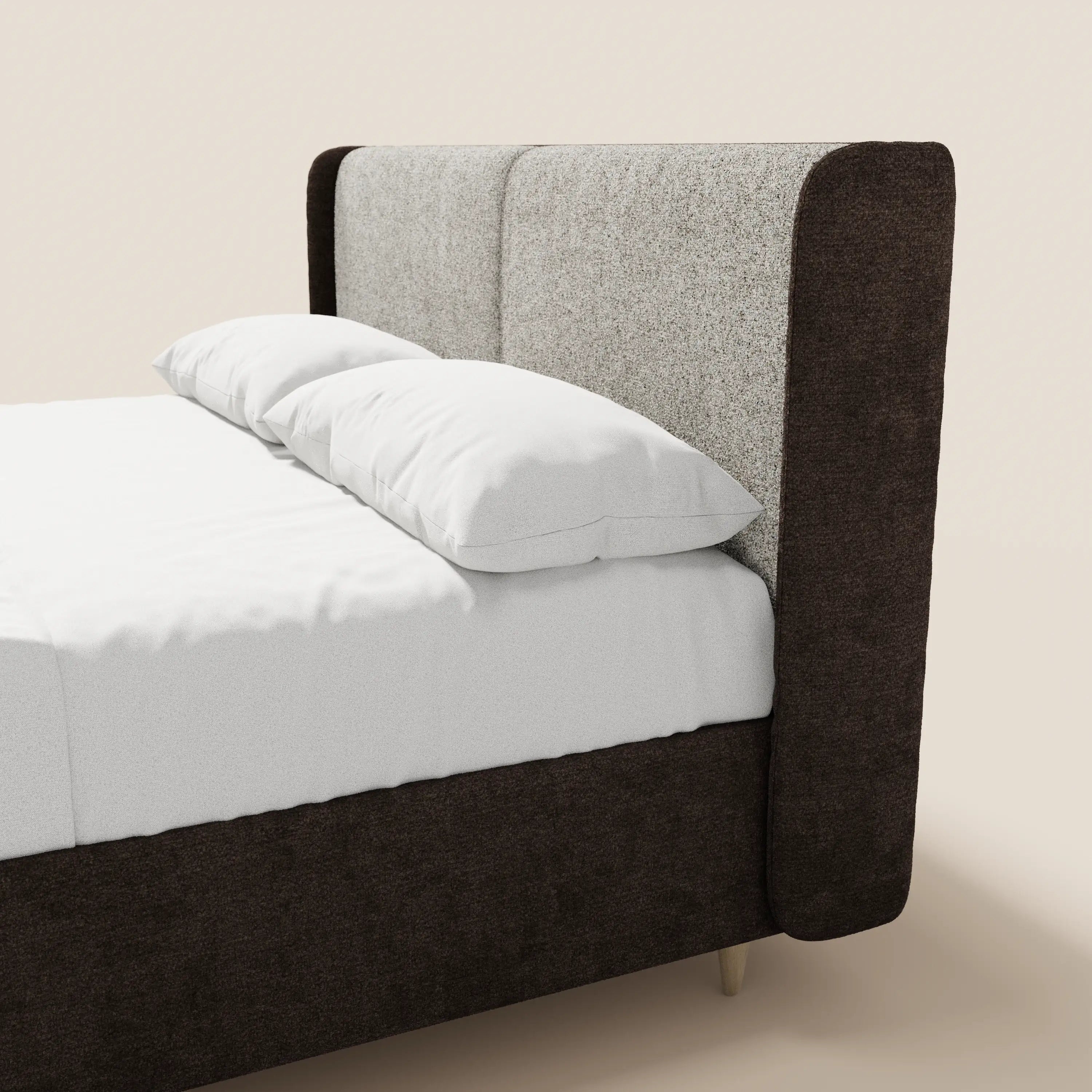 Il letto imbottito bicolore VALKIRIA di Letti.store presenta una testiera alta e ricurva in due tonalità, grigio chiaro e marrone scuro, con cuscini schienali e vano contenitore, poggiata su gambe in legno chiaro su uno sfondo beige.