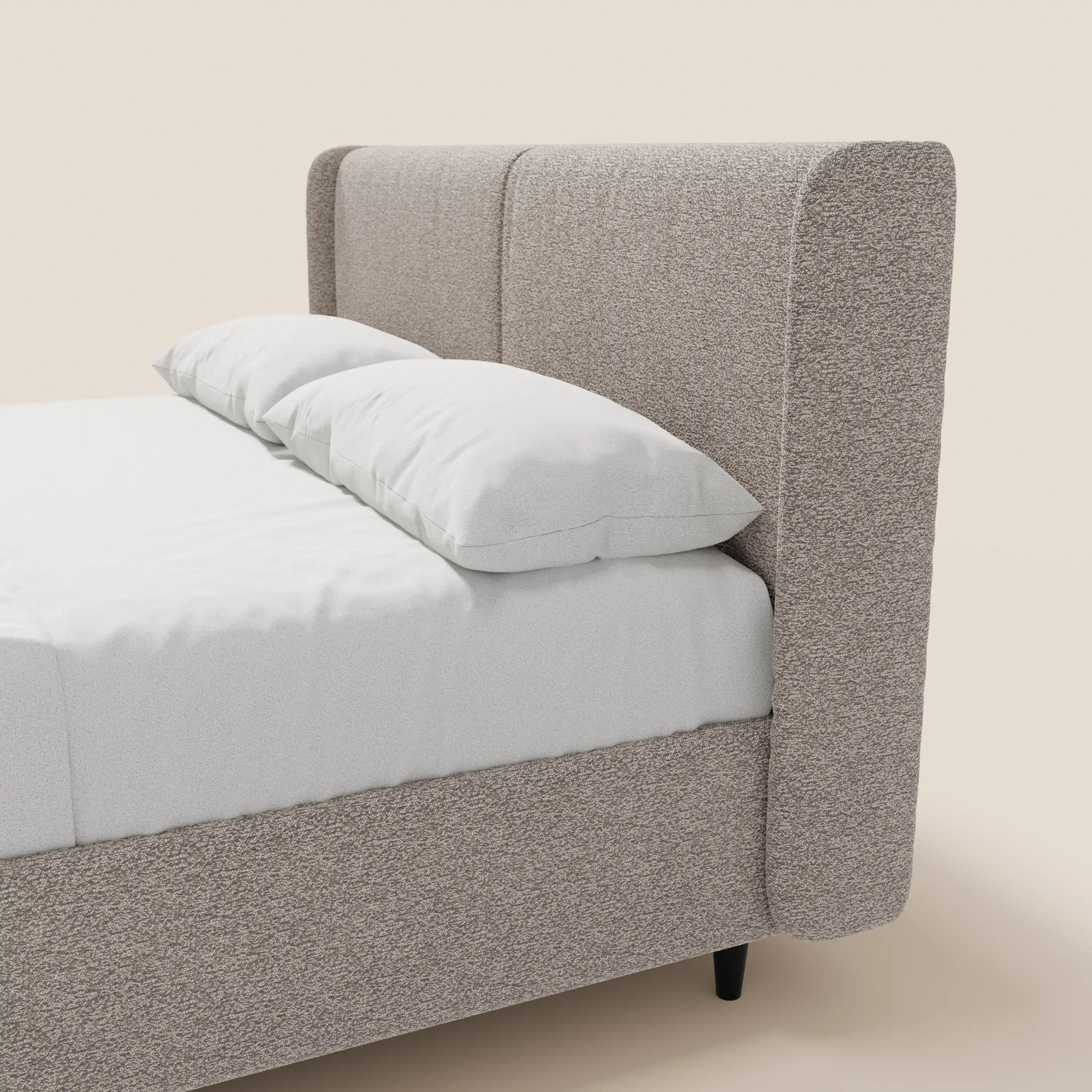 Una vista laterale ravvicinata del letto di design VALKIRIA di Letti.store, realizzato in tessuto Oeko-Tex®, con una testiera avvolgente dotata di 2 cuscini imbottiti, un vano contenitore e un elegante stile contemporaneo su uno sfondo chiaro.