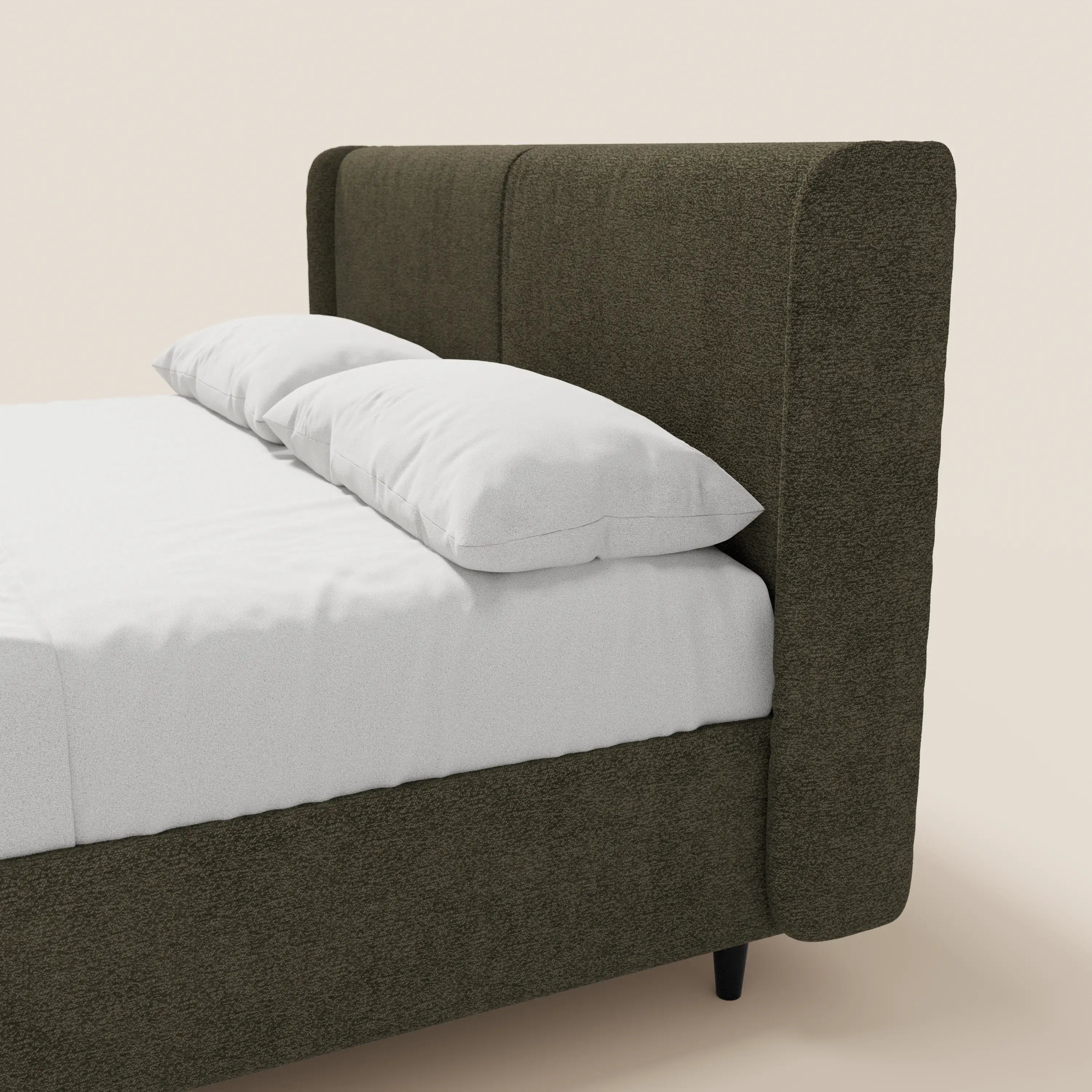 VALKIRIA di Letti.store è un letto di design con contenitore, testiera avvolgente e 2 cuscini imbottiti in tessuto Oeko-Tex®, presentato in verde oliva scuro con gambe nere corte e biancheria bianca su sfondo beige.