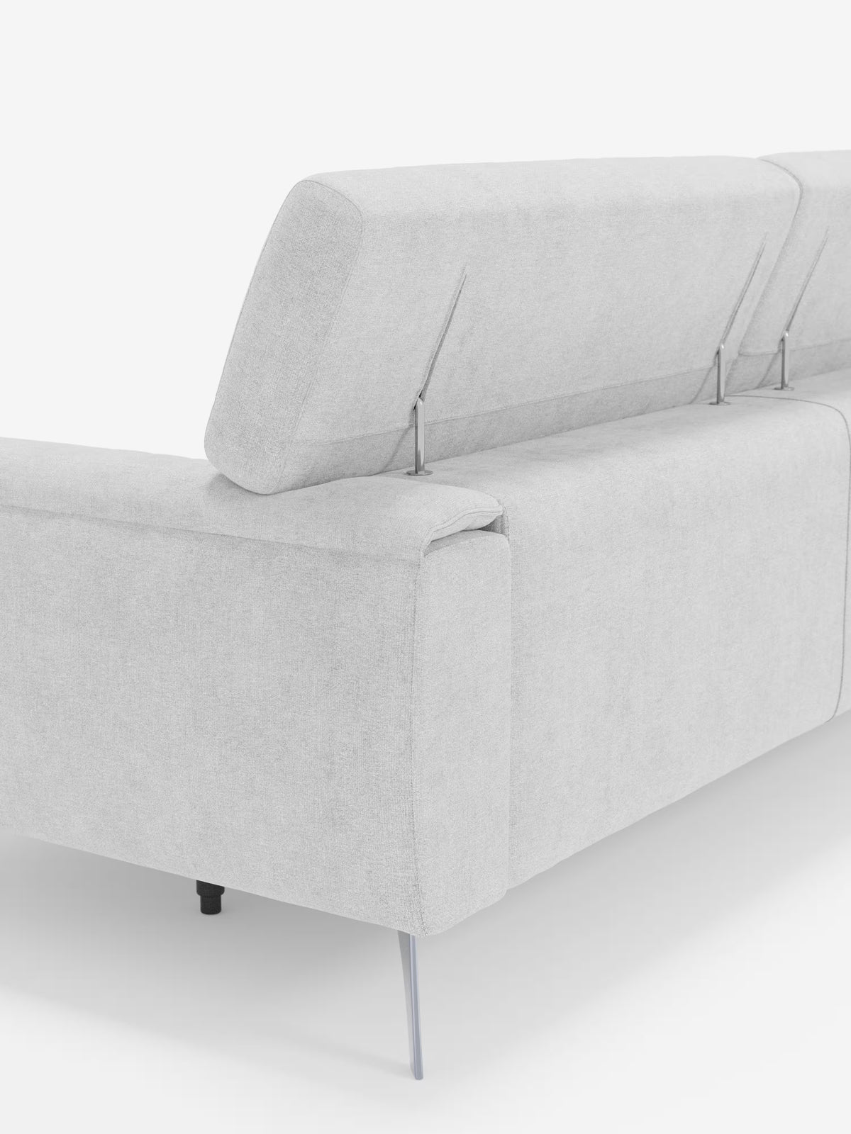 Un primo piano del divano Caravaggio a 2 e 3 posti di Divani.Store in grigio chiaro, realizzato in elegante tessuto smacchiabile T31, mette in risalto un poggiatesta regolabile con supporti in metallo e sottili gambe metalliche su uno sfondo bianco. Sono visibili solo la parte posteriore e una parte di un bracciolo, a sottolineare il design contemporaneo del divano, le linee pulite e le sedute allungabili.