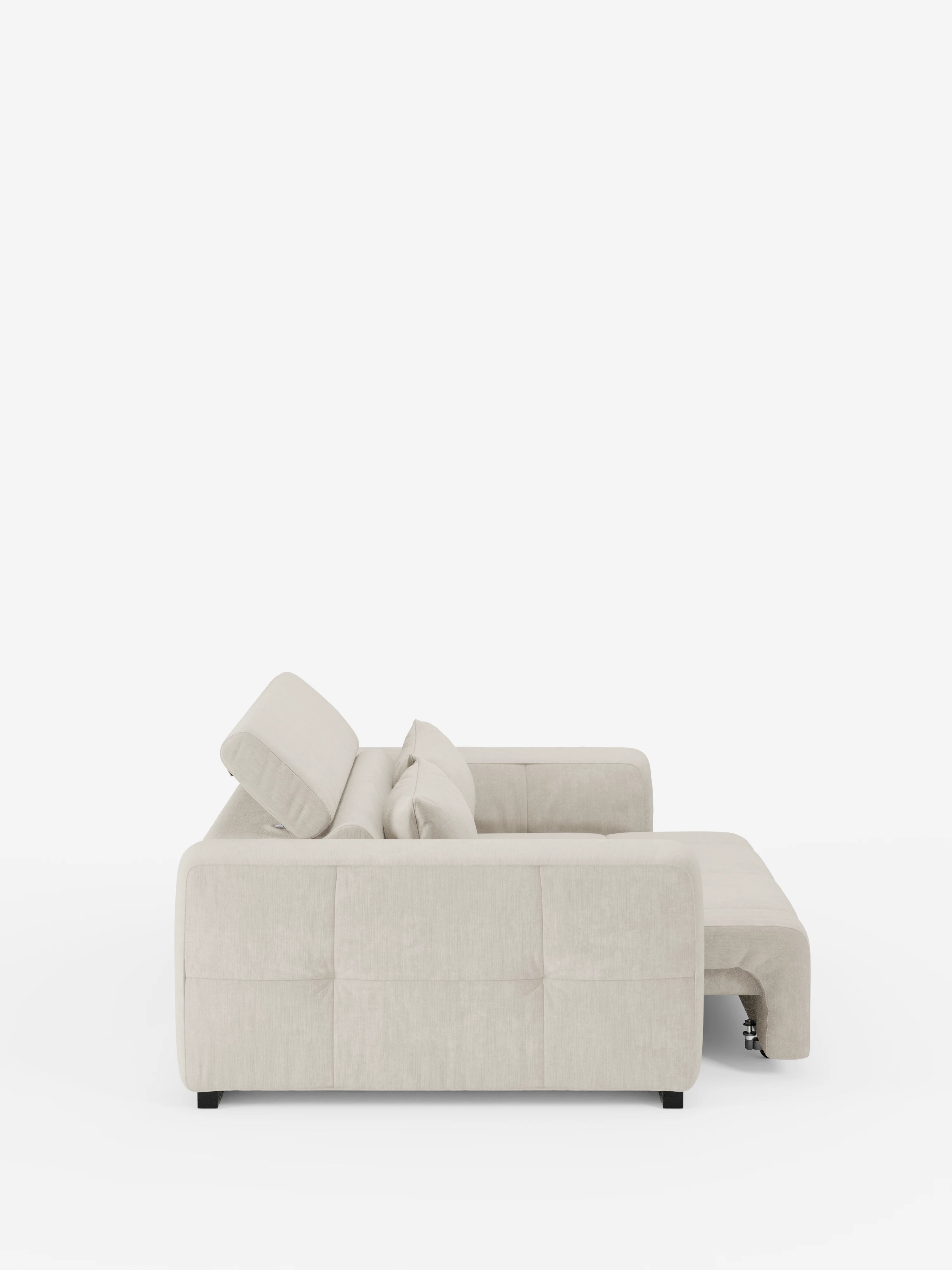 Vista laterale del divano Monarch con relax elettrico per l'allungamento delle sedute e poggiatesta reclinabile di Divani.Store, rivestito in morbido tessuto T31 antimacchia in una moderna tonalità di beige chiaro. La chaise longue si estende verso destra e il design elegante e contemporaneo presenta dettagli trapuntati minimalisti e piedini neri. Questo sofisticato divano contemporaneo è messo in risalto su uno sfondo bianco a tinta unita.