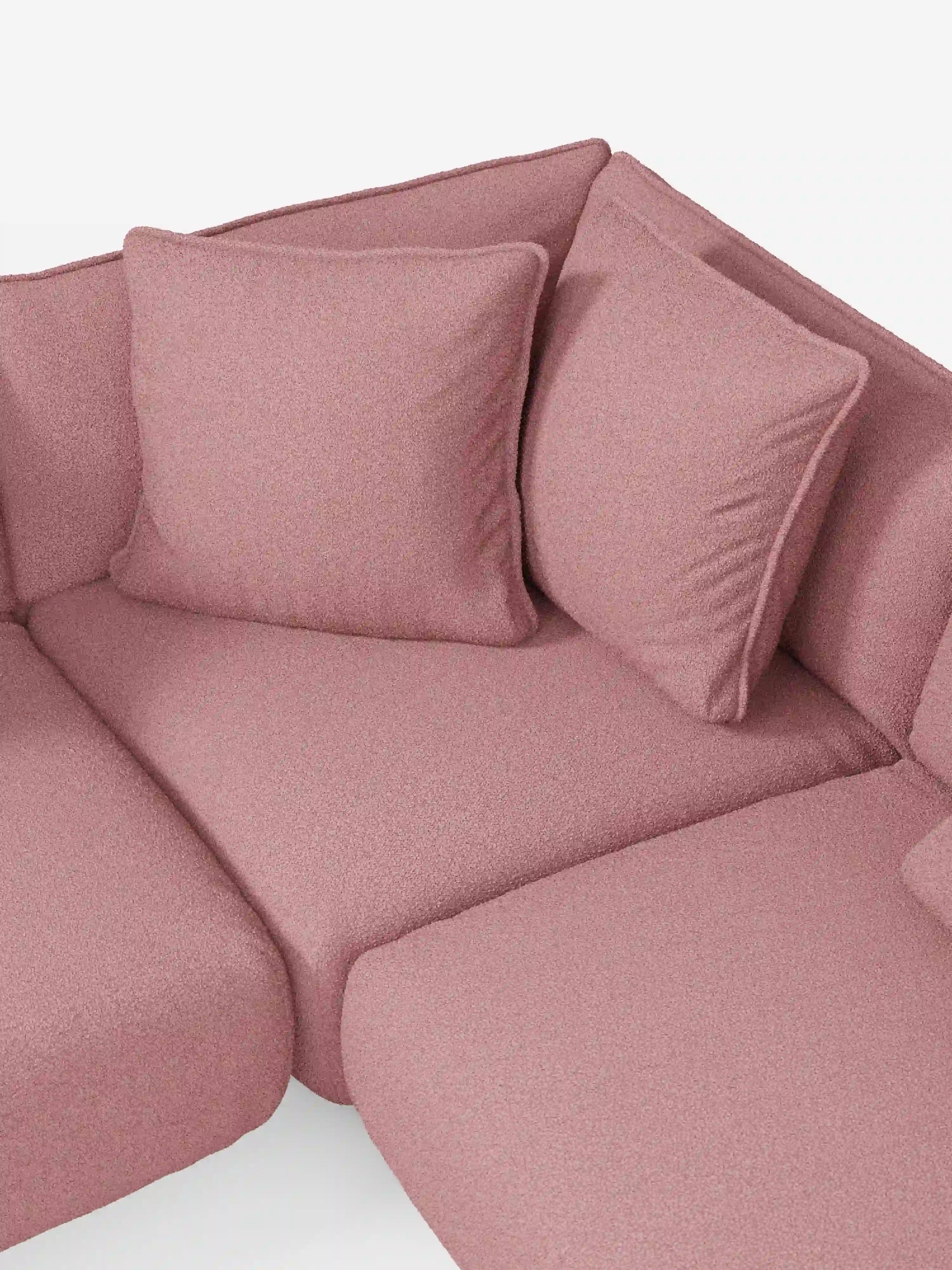 Un primo piano del divano angolare panoramico componibile Nimbus con penisola e angolo in tessuto smacchiabile T33 di Divani.Store mette in risalto il suo tessuto morbido, strutturato e resistente alle macchie, in colore rosa. Il divano componibile presenta due grandi cuscini coordinati, disposti ordinatamente nell’angolo contro lo schienale. Le linee pulite e il design moderno sottolineano l’eccezionale qualità e l’artigianalità italiana che contraddistinguono i mobili Divani.Store.