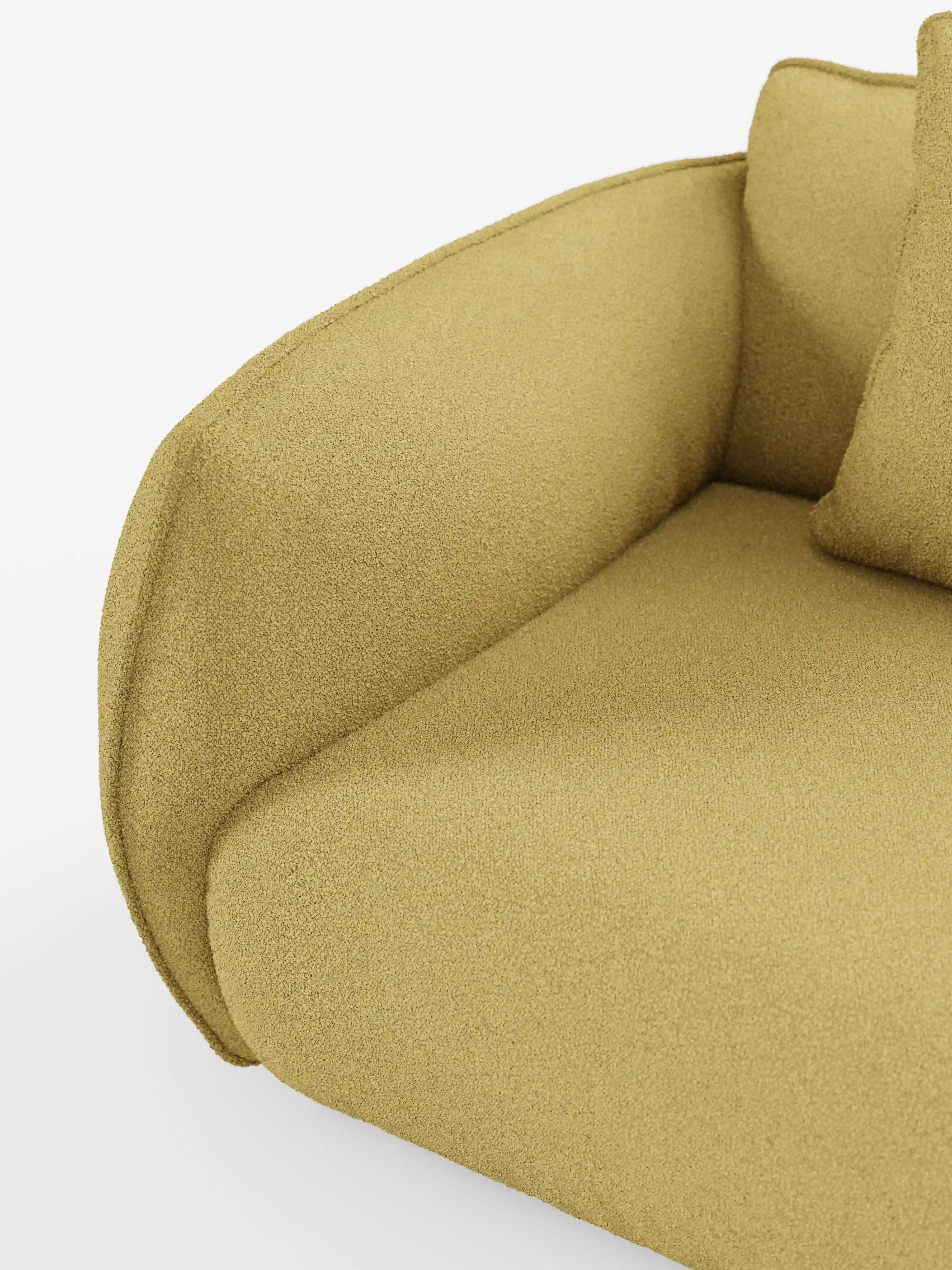 Primo piano del divano angolare con penisola componibile Nimbus di Divani.Store, rivestito in morbido tessuto effetto cotone T33, resistente alle macchie, color giallo senape. L’immagine mette in risalto il bracciolo arrotondato, il cuscino della seduta e una parte dello schienale, evidenziandone la consistenza morbida e l’aspetto accogliente. Uno sfondo bianco a tinta unita esalta il colore vivace del divano e la consistenza tattile del tessuto.