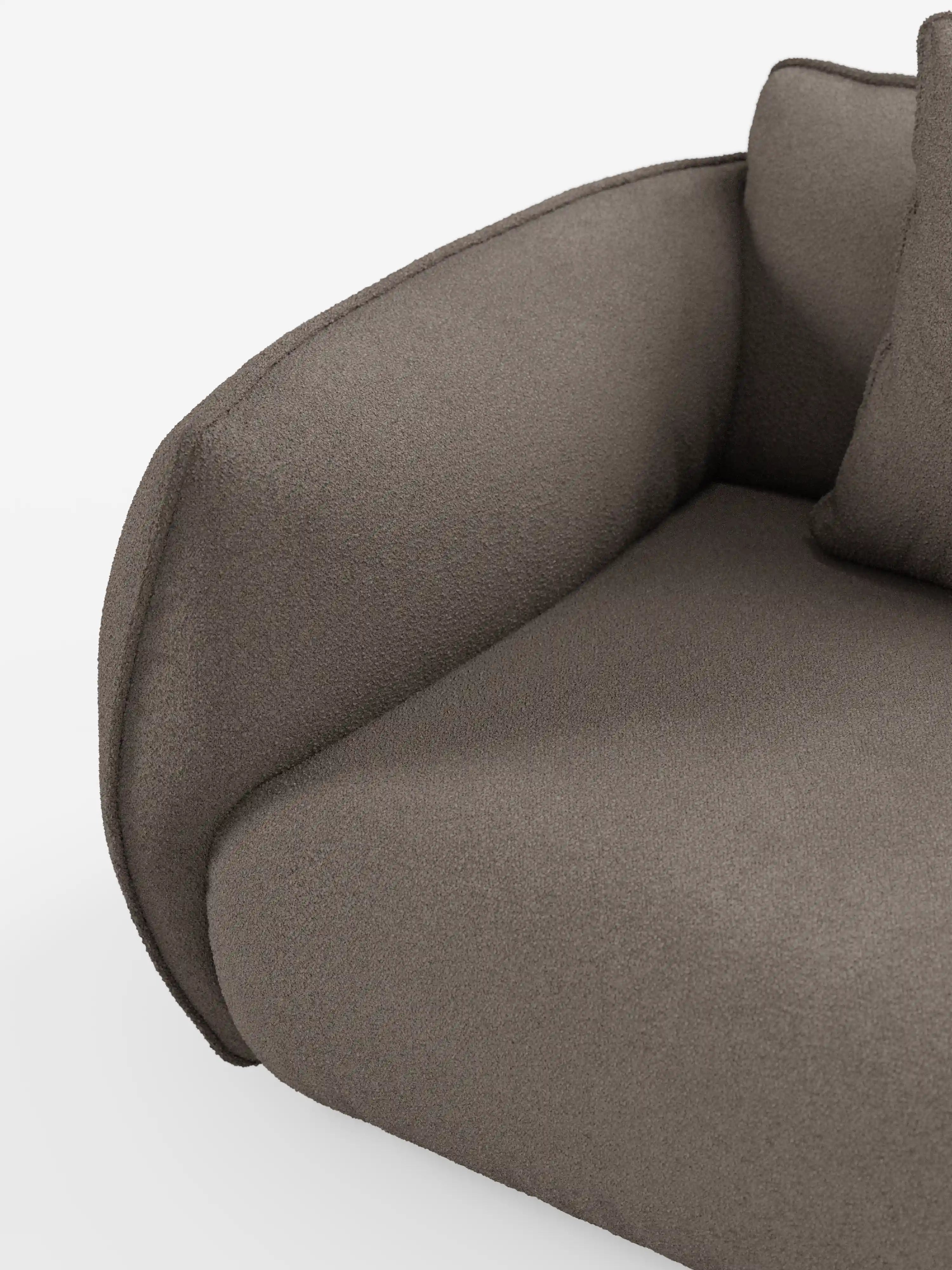 Primo piano del divano angolare con penisola componibile Nimbus di Divani.Store, rivestito in morbido tessuto T33 effetto cotone, resistente alle macchie, in una moderna tonalità taupe. L’immagine mostra il bracciolo, la seduta e parte del cuscino dello schienale su uno sfondo bianco. Questo divano modulare contemporaneo presenta linee morbide e arrotondate e un aspetto lussuoso e accogliente.