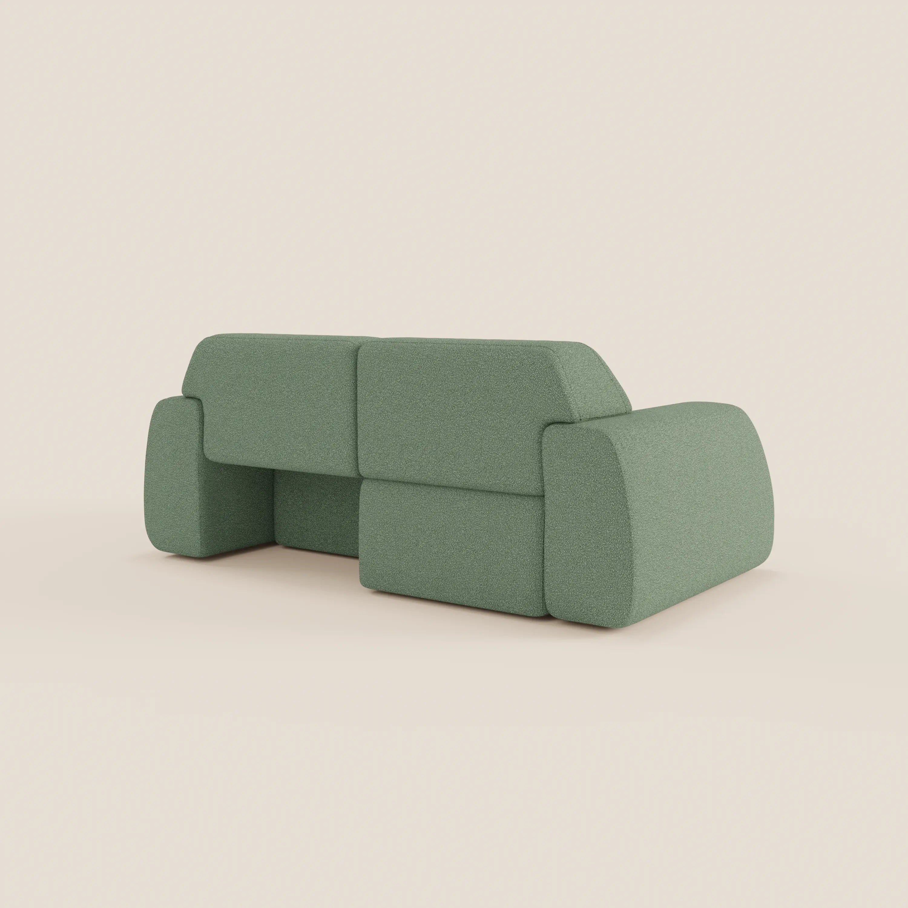 Il divano Orbit 2 e 3 posti di Divani.Store, visto di schiena e di lato, è caratterizzato da forme geometriche a blocchi, bordi arrotondati, assenza di gambe visibili e tessuto verde chiaro smacchiabile effetto cotone T33. Completamente sfoderabile. Fondo bianco sporco a tinta unita.