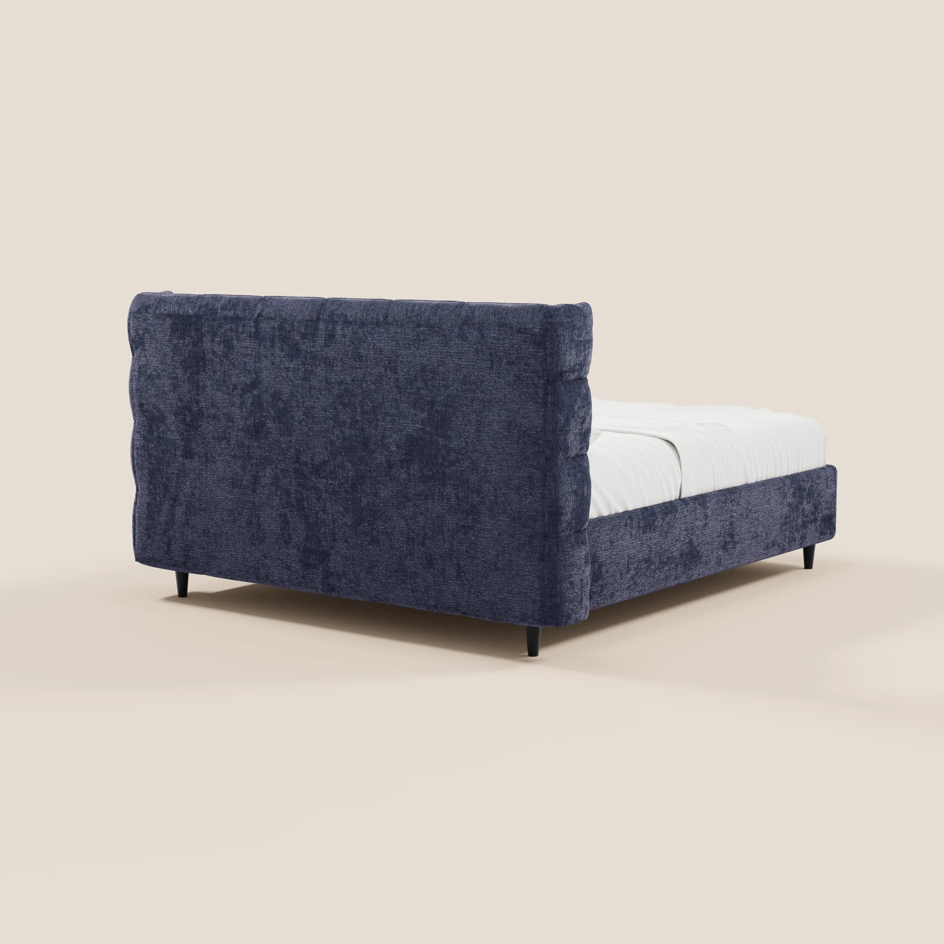 Il letto imbottito RAGNAR con contenitore di Letti.store presenta una testiera capitonné avvolgente, un elegante rivestimento blu in tessuto certificato Oeko-Tex®, una base rialzata da corti piedini neri e biancheria da letto bianca ben sistemata sul materasso.