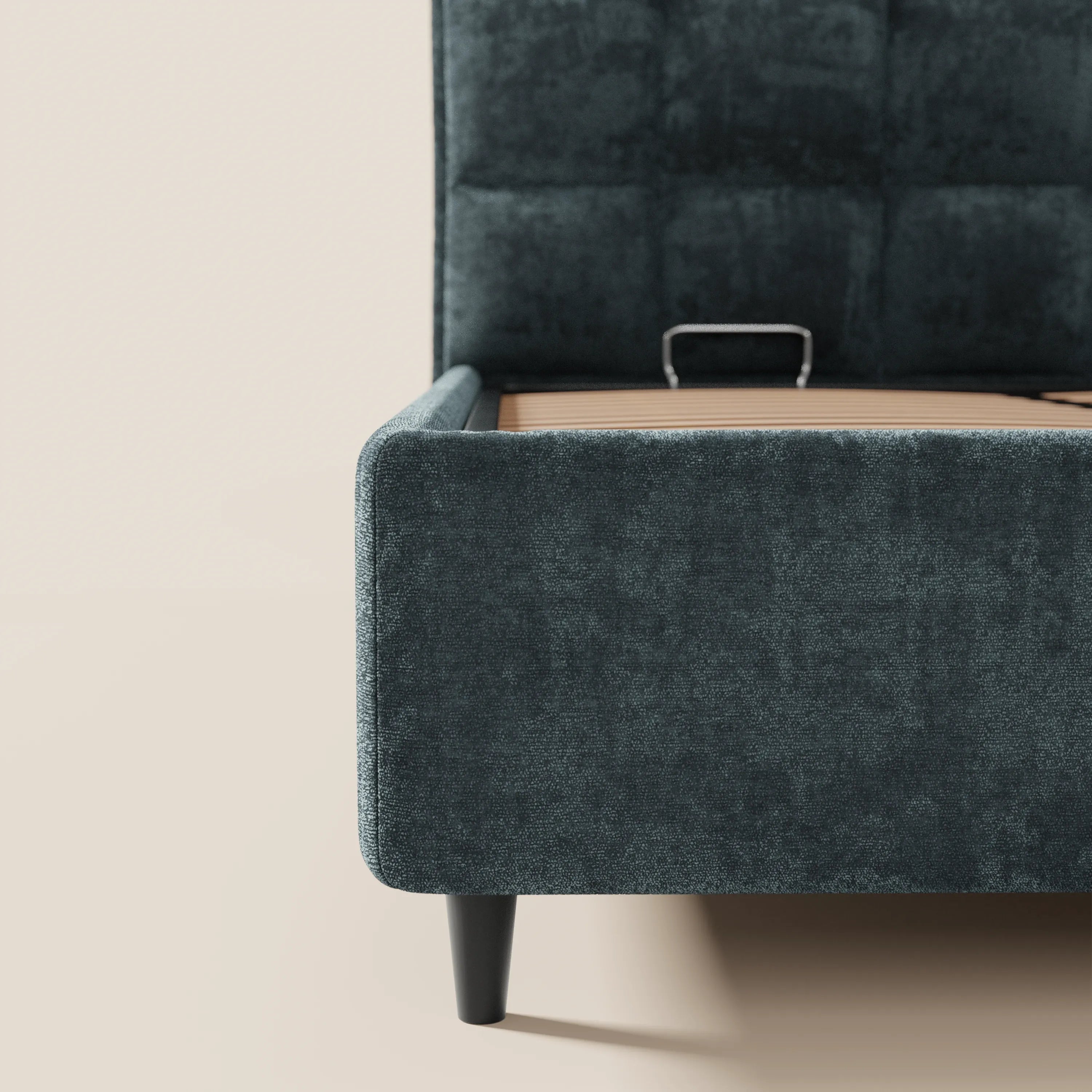 Un primo piano del letto imbottito AURO di Letti.store, realizzato in ciniglia color verde acqua scuro certificata Oeko-Tex®, mostra la pediera, la sponda laterale e l'alta testiera capitonné, con brevi gambe nere che risaltano su uno sfondo beige neutro.