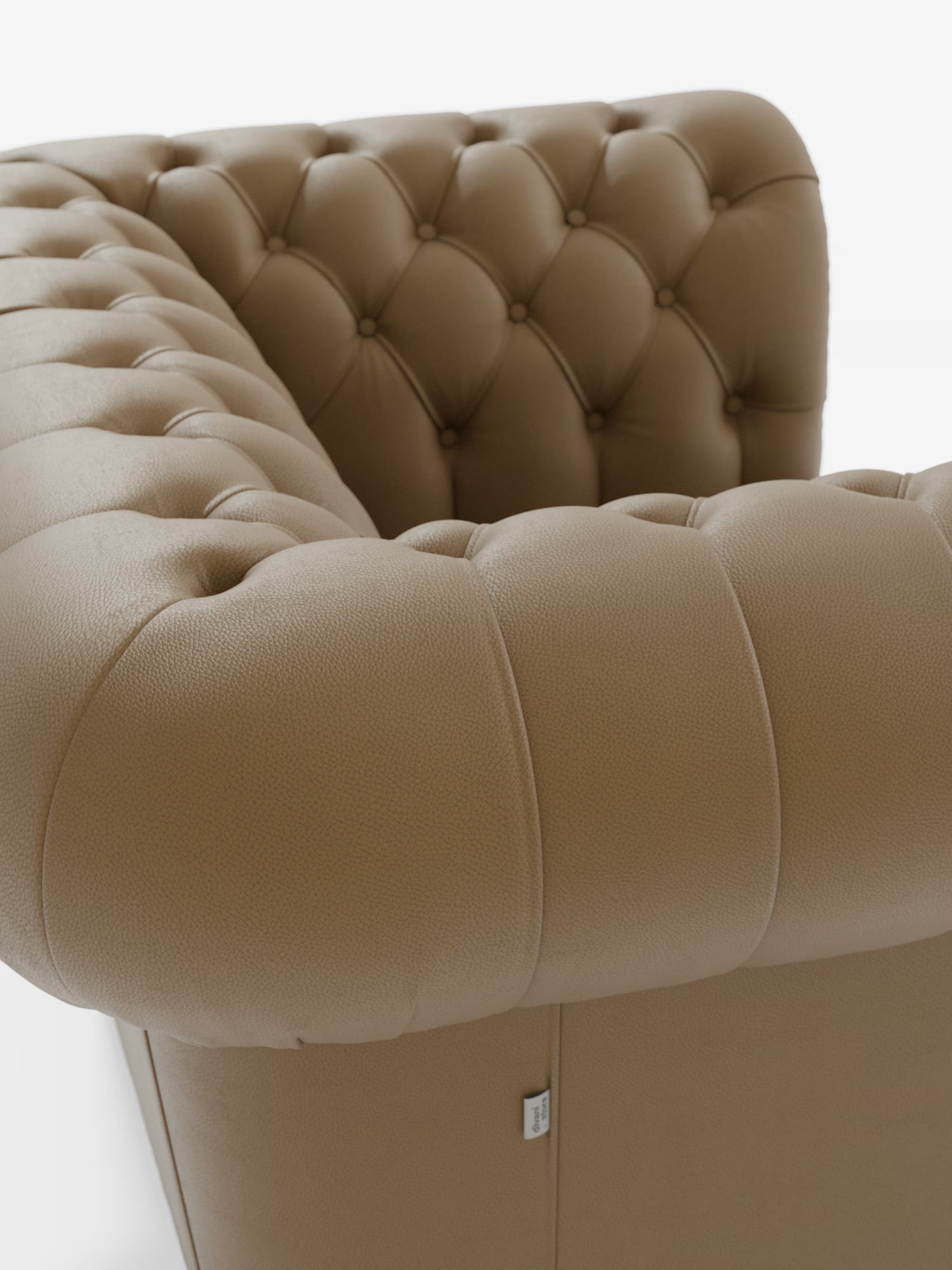 Primo piano della poltrona Chester in vera pelle spessorata con capitonné artigianale di Divani.Store, che mette in risalto lo schienale e i braccioli della poltrona in pelle color cuoio, con i classici dettagli a bottoni della lavorazione capitonné e il rivestimento testurizzato. Su uno sfondo bianco a tinta unita, l’immagine mette in risalto il design lussuoso e raffinato della poltrona, le cuciture curate e una piccola etichetta in tessuto visibile nella parte inferiore.