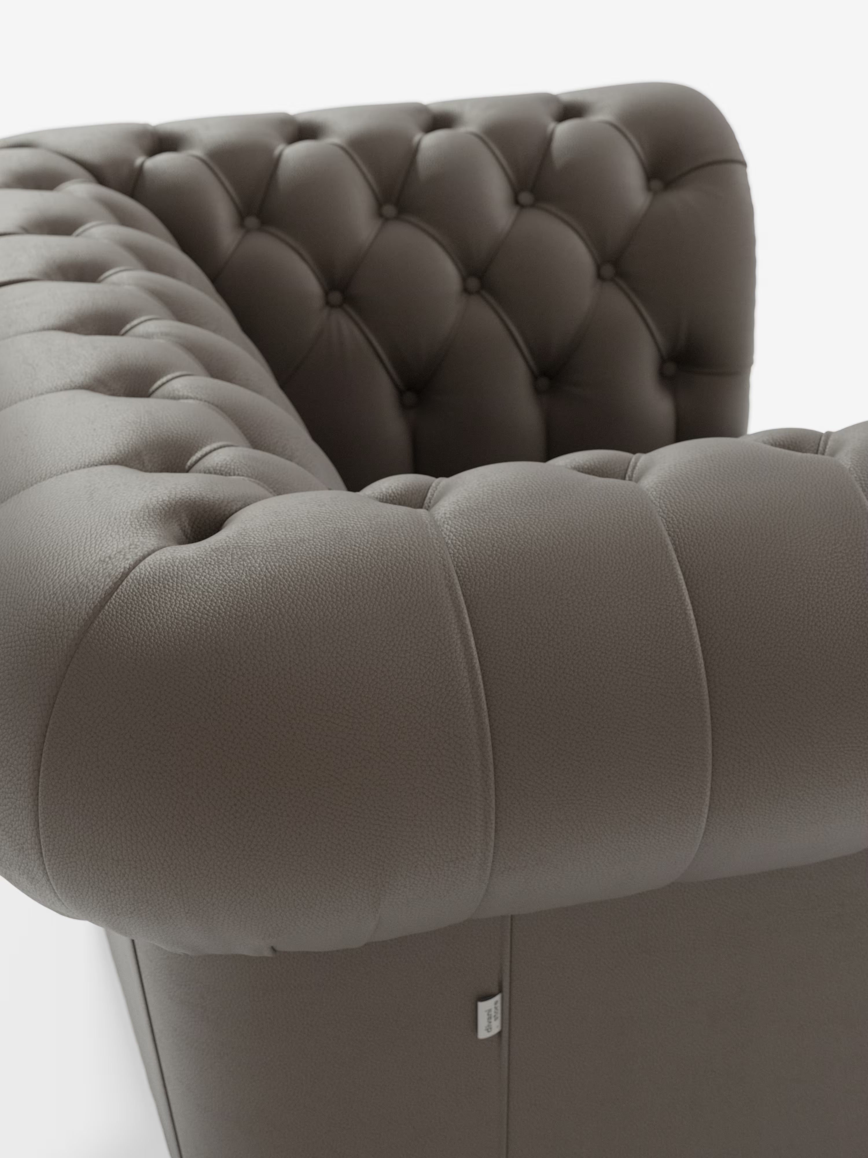Primo piano della poltrona Chester in vera pelle spessorata con capitonné artigianale di Divani.Store: una poltrona in pelle marrone scuro con capitonné, caratterizzata da profondi bottoni decorativi e braccioli arrotondati, su sfondo bianco. Questa elegante poltrona in pelle presenta una raffinata lavorazione capitonné, che mette in risalto la texture raffinata e la maestria artigianale del suo rivestimento.