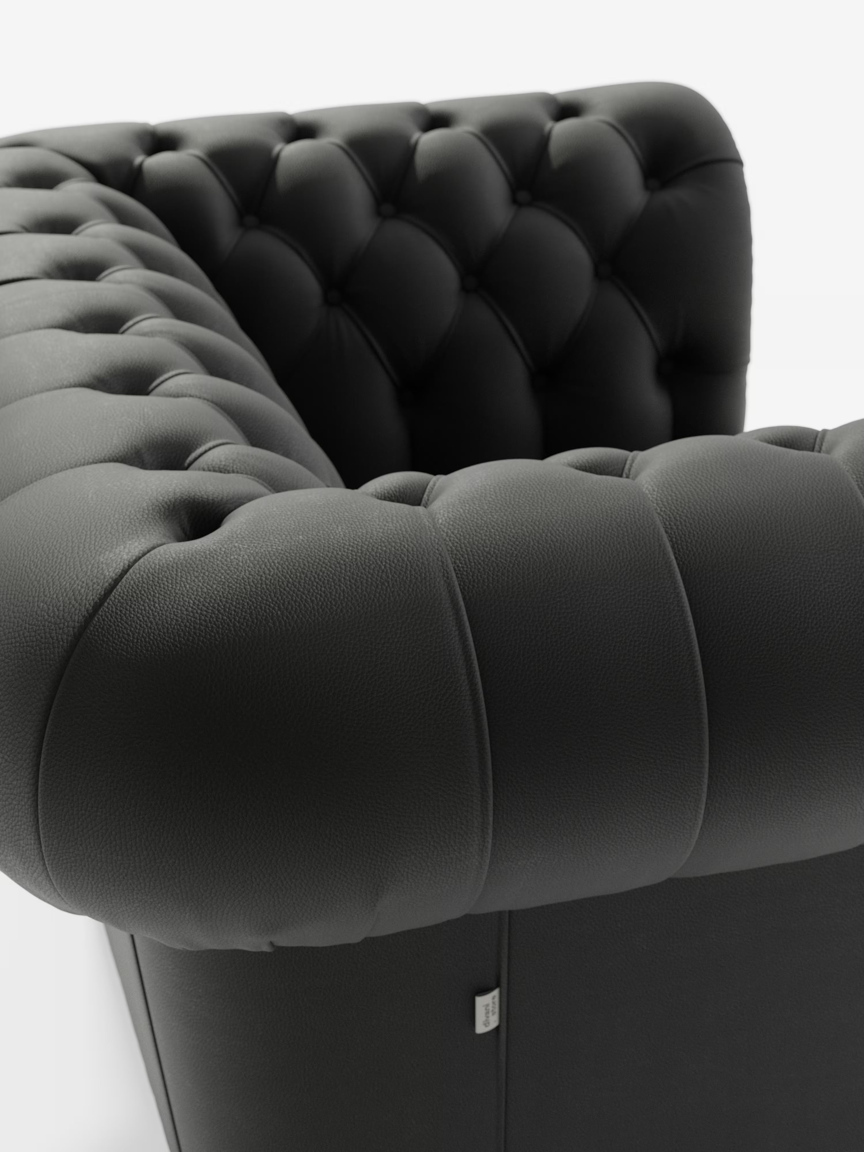 Primo piano della poltrona Chester in vera pelle spessorata con capitonné artigianale di Divani.Store, caratterizzata da un rivestimento in pelle nera trapuntata con profondi bottoni decorativi sullo schienale e sui braccioli. La superficie liscia ma leggermente ruvida al tatto e la morbidezza al tatto esaltano la raffinata maestria artigianale e lo stile classico della poltrona capitonné.