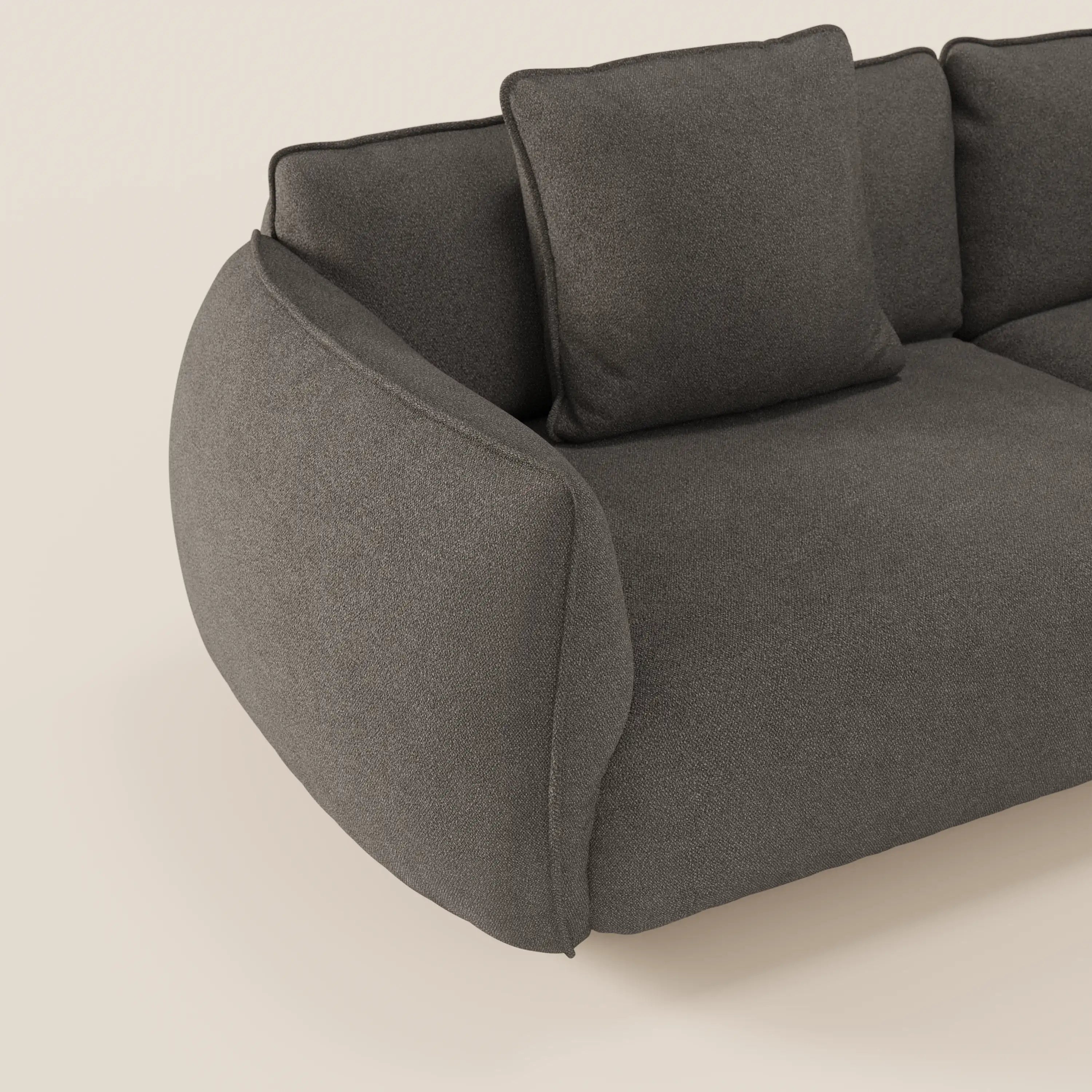 Primo piano del divano modulare a 3 sedute Nimbus di Divani.Store in grigio scuro, con rivestimento in smacchiabile effetto cotone T33, un bracciolo, due cuscini e un design morbido e arrotondato su uno sfondo beige chiaro.