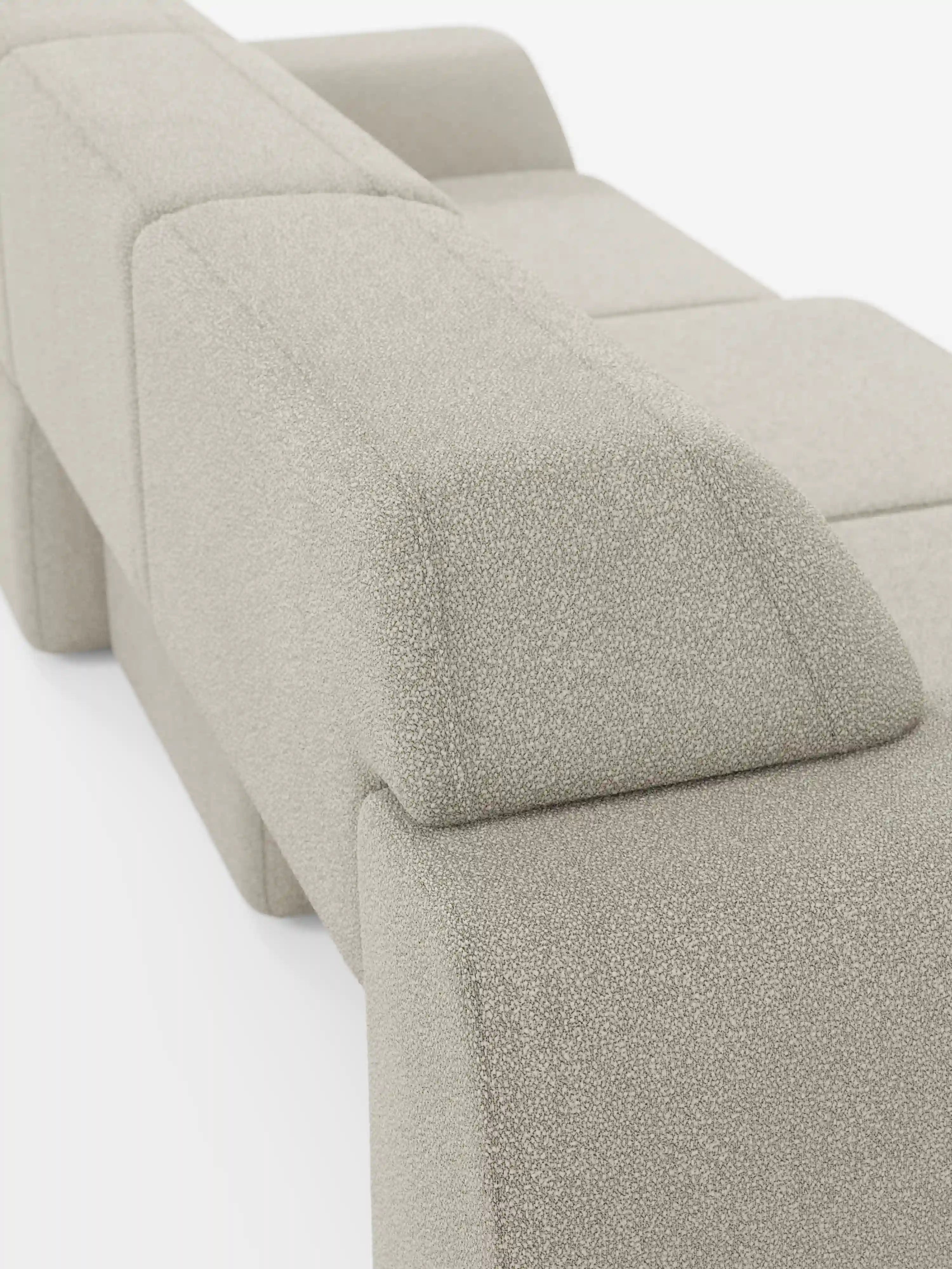 Un primo piano dello schienale e del bracciolo del moderno divano Orbit con 3 sedute scorrevoli e allungabili in tessuto effetto cotone smacchiabile T33 di Divani.Store, caratterizzato da un tessuto beige chiaro a trama ruvida con motivi geometrici a blocchi e linee pulite, su uno sfondo bianco a tinta unita.