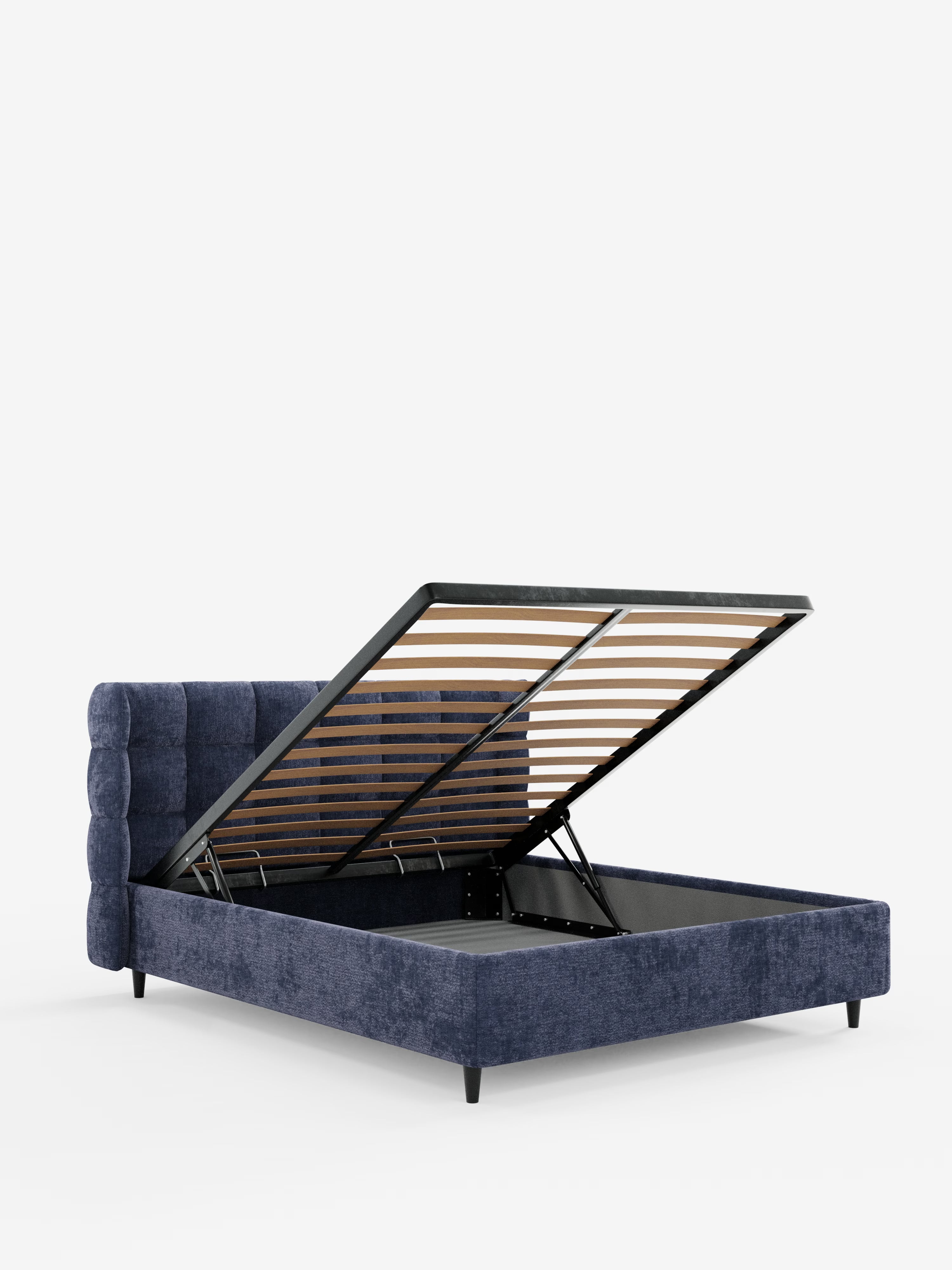 Il letto imbottito RAGNAR con contenitore e testiera capitonné avvolgente di Letti.store, rivestito in un elegante tessuto certificato Oeko-Tex®, presenta un’alta testiera capitonné avvolgente di colore blu che costituisce uno splendido punto focale. La sua rete a doghe si solleva facilmente per rivelare un ampio vano contenitore sotto il materasso. La raffinata struttura poggia su corte gambe nere ed è fotografata su uno sfondo bianco a tinta unita.