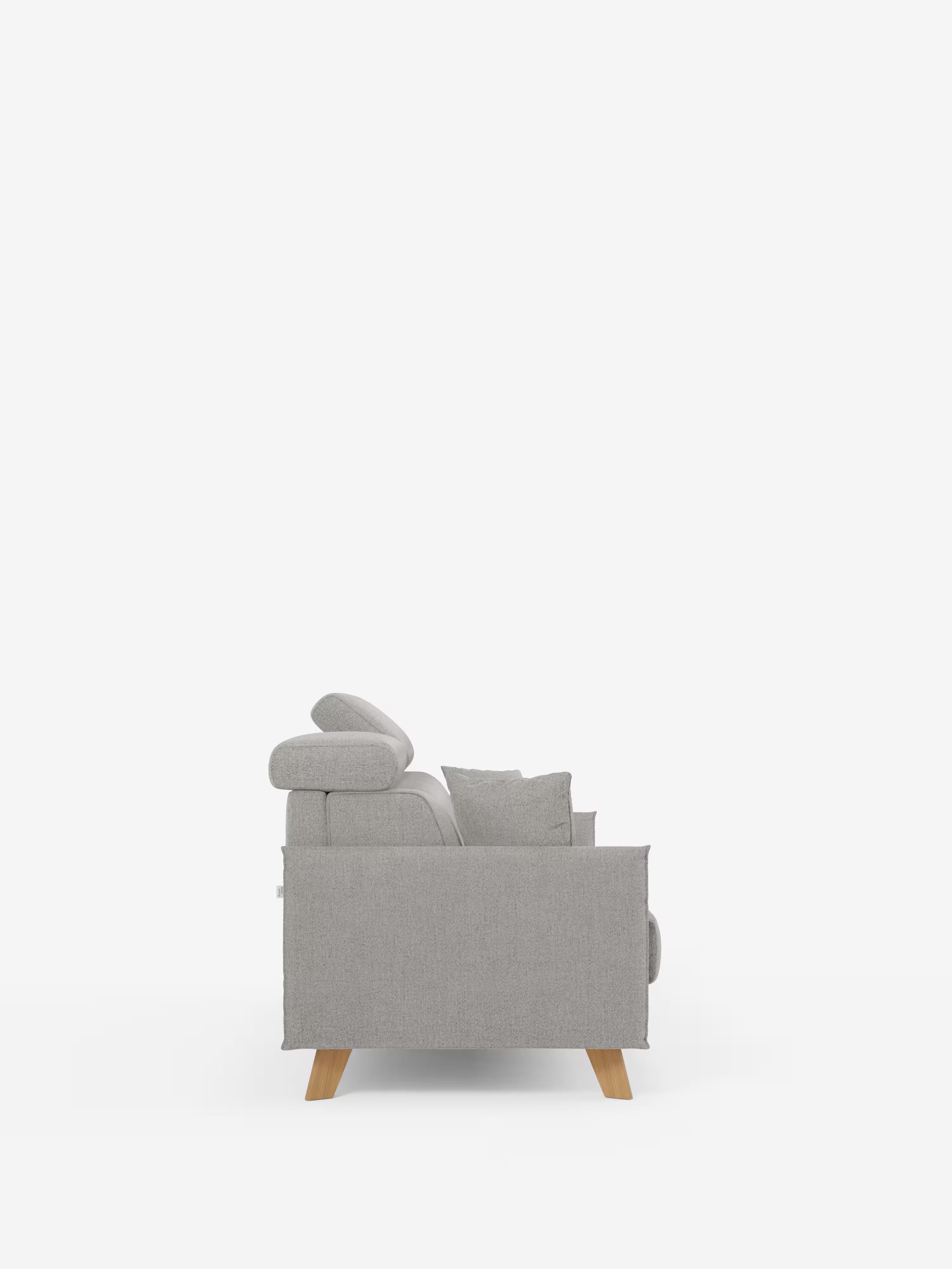 Vista laterale del divano letto matrimoniale Sole dal design compatto di Divani.Store, rivestito in tessuto T23 grigio chiaro antimacchia, dotato di due cuscini di seduta, un cuscino dello schienale, braccioli imbottiti, poggiatesta reclinabili e quattro gambe in legno chiaro. Lo sfondo è bianco a tinta unita.