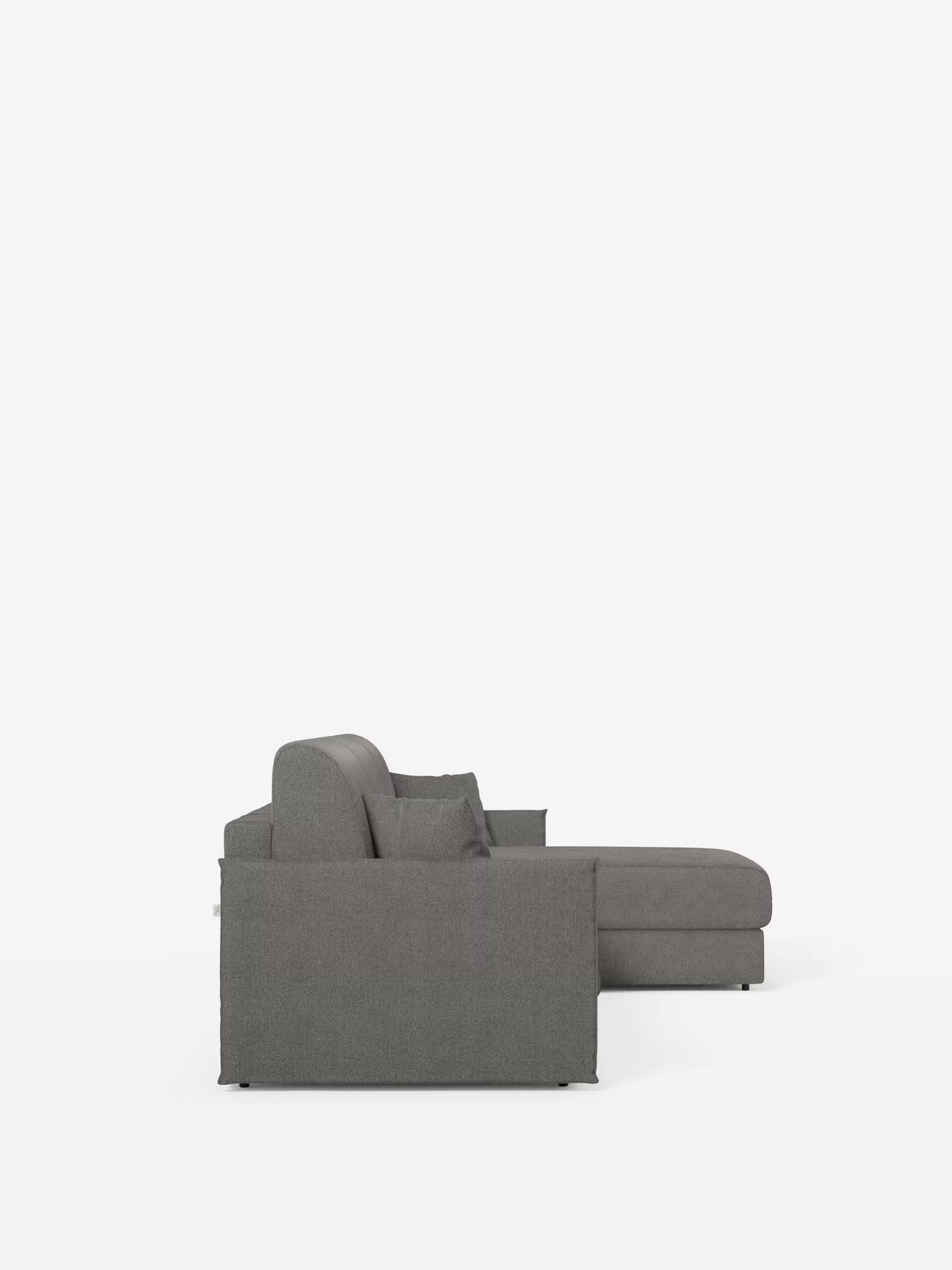 Vista laterale del divano letto angolare con penisola contenitore Evans di Divani.Store, caratterizzato da un design moderno in tessuto grigio dalle linee pulite, con un unico bracciolo sinistro e una chaise longue che si estende verso destra. Su uno sfondo bianco a tinta unita, la silhouette compatta in tessuto T23 antimacchia mette in risalto l’estetica minimalista del divano.