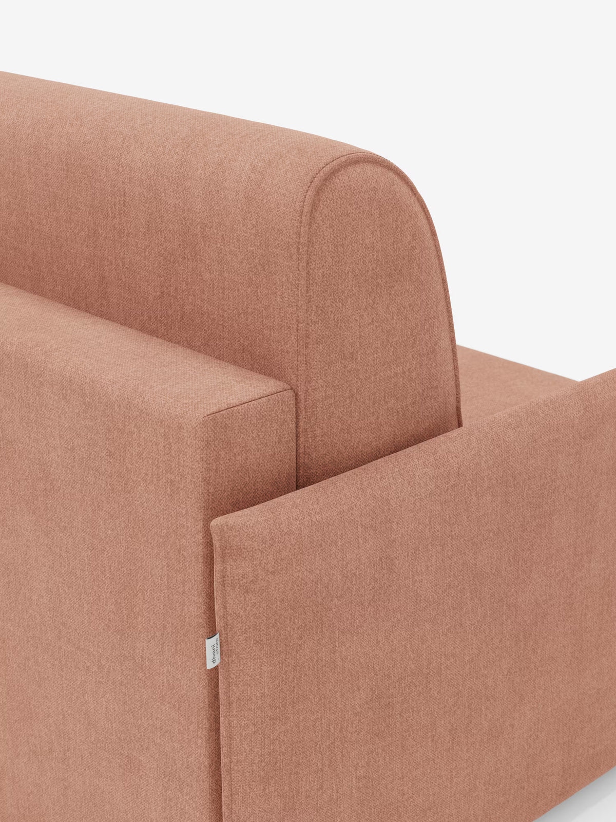 Primo piano della poltrona letto compatta Evans con materasso di Divani.Store, rivestita in tessuto T23 color terracotta tenue, resistente alle macchie e sfoderabile. L’immagine mette in risalto lo schienale e i braccioli, evidenziando il rivestimento morbido e strutturato del divano, con una piccola etichetta in tessuto bianco sul bracciolo. Questo versatile complemento d’arredo funge anche da letto singolo salvaspazio (poltrona letto singola), rendendolo ideale per gli spazi abitativi ridotti. Lo sfondo