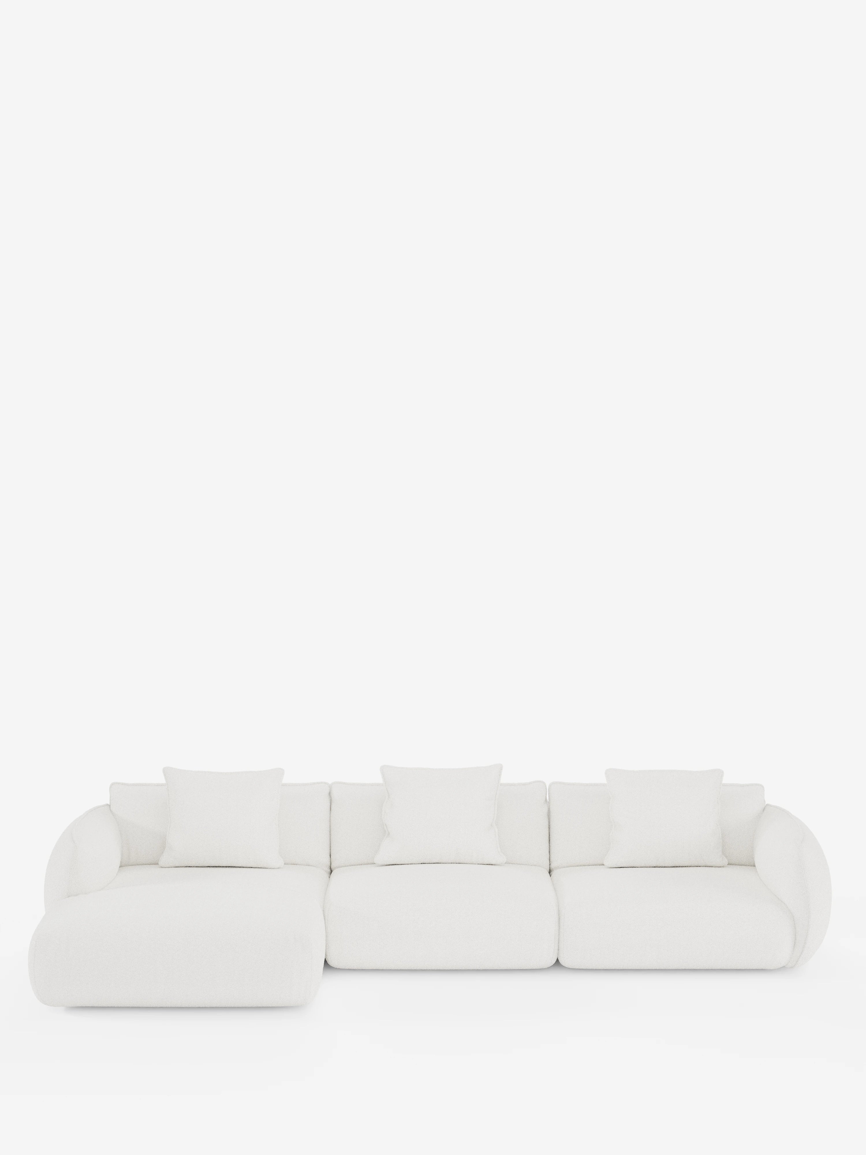 Il divano angolare con penisola componibile Nimbus di Divani.Store è un moderno divano componibile bianco rivestito in morbido tessuto effetto cotone resistente alle macchie (T33), con tre posti e una chaise longue a sinistra. È caratterizzato da cinque cuscini quadrati coordinati, braccioli arrotondati e un design minimalista, che risalta su uno sfondo bianco a tinta unita.