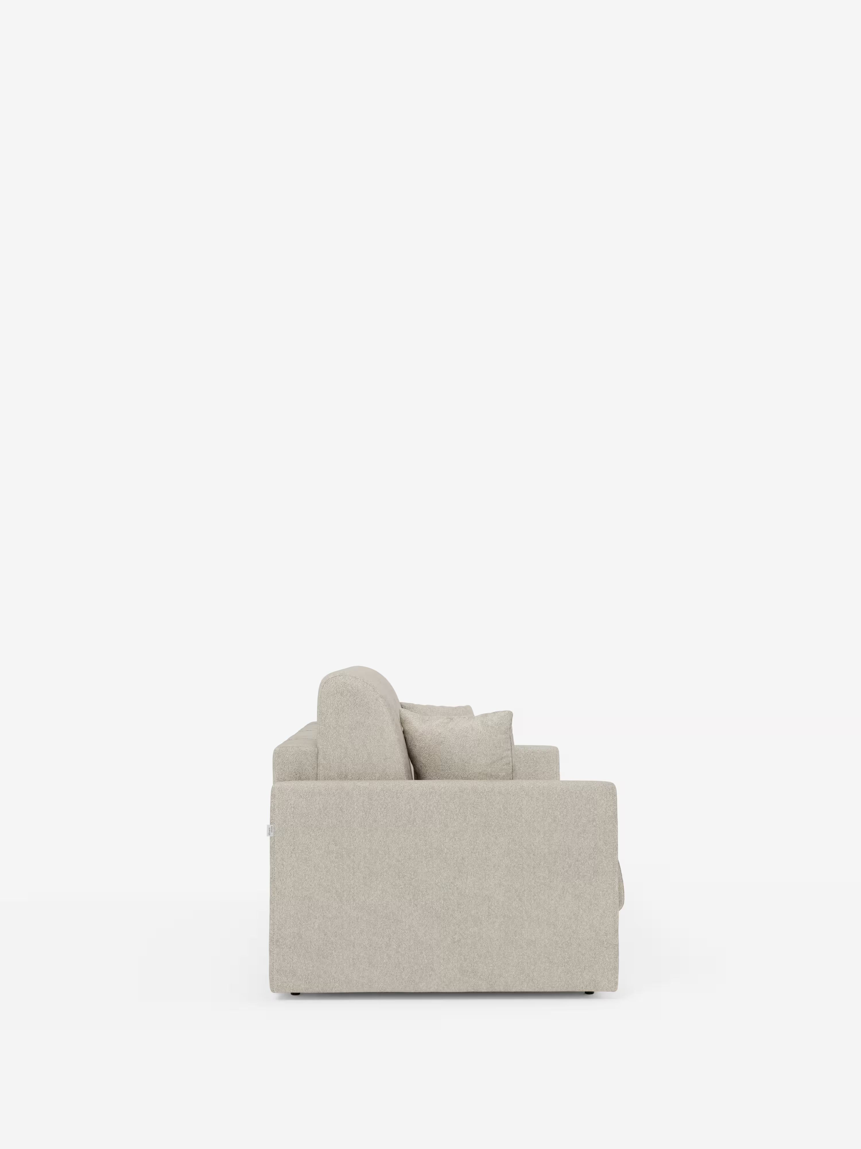 Vista laterale del divano letto Tommy a 2 e 3 posti matrimoniale di Divani.Store: un divano moderno color beige chiaro, rivestito in tessuto T33 smacchiabile effetto cotone. Questo divano, sfoderabile al 100%, presenta un design squadrato con braccioli dritti e sottili (braccioli slim), morbidi cuscini di seduta e schienale e un cuscino decorativo. Sullo sfondo bianco, la forma compatta di questo divano letto è protagonista dell’immagine.