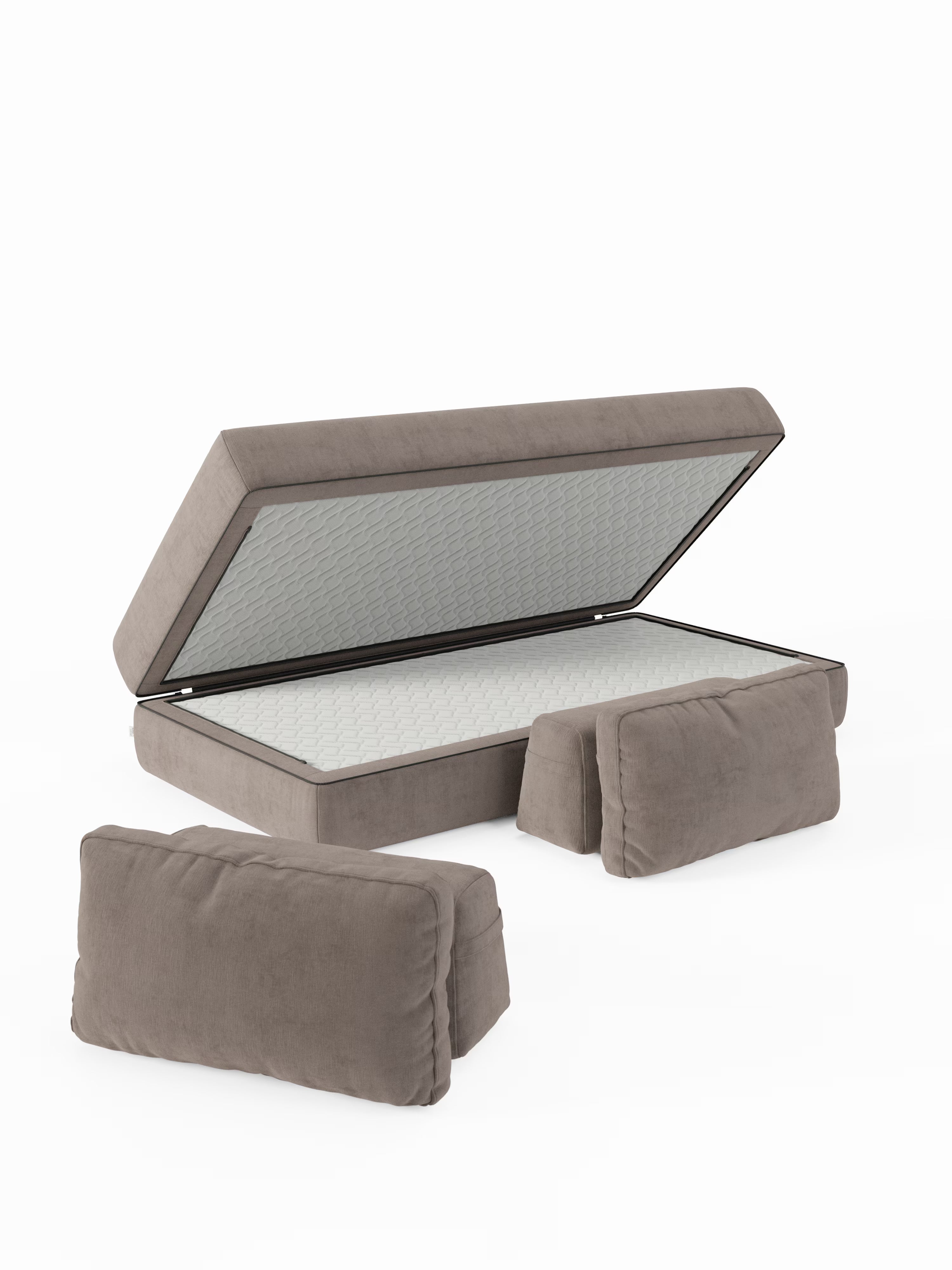 Il divano letto matrimoniale Rift di Divani.Store è qui raffigurato con la piattaforma del materasso sollevata, a rivelare l’ampio vano contenitore interno, ideale per riporre in modo ordinato la biancheria di ricambio o il materasso in memory foam T31 da 22 cm di altezza incluso nella dotazione. Due cuscini imbottiti coordinati color cuoio sono posizionati nella parte anteriore, il tutto su uno sfondo bianco a tinta unita.
