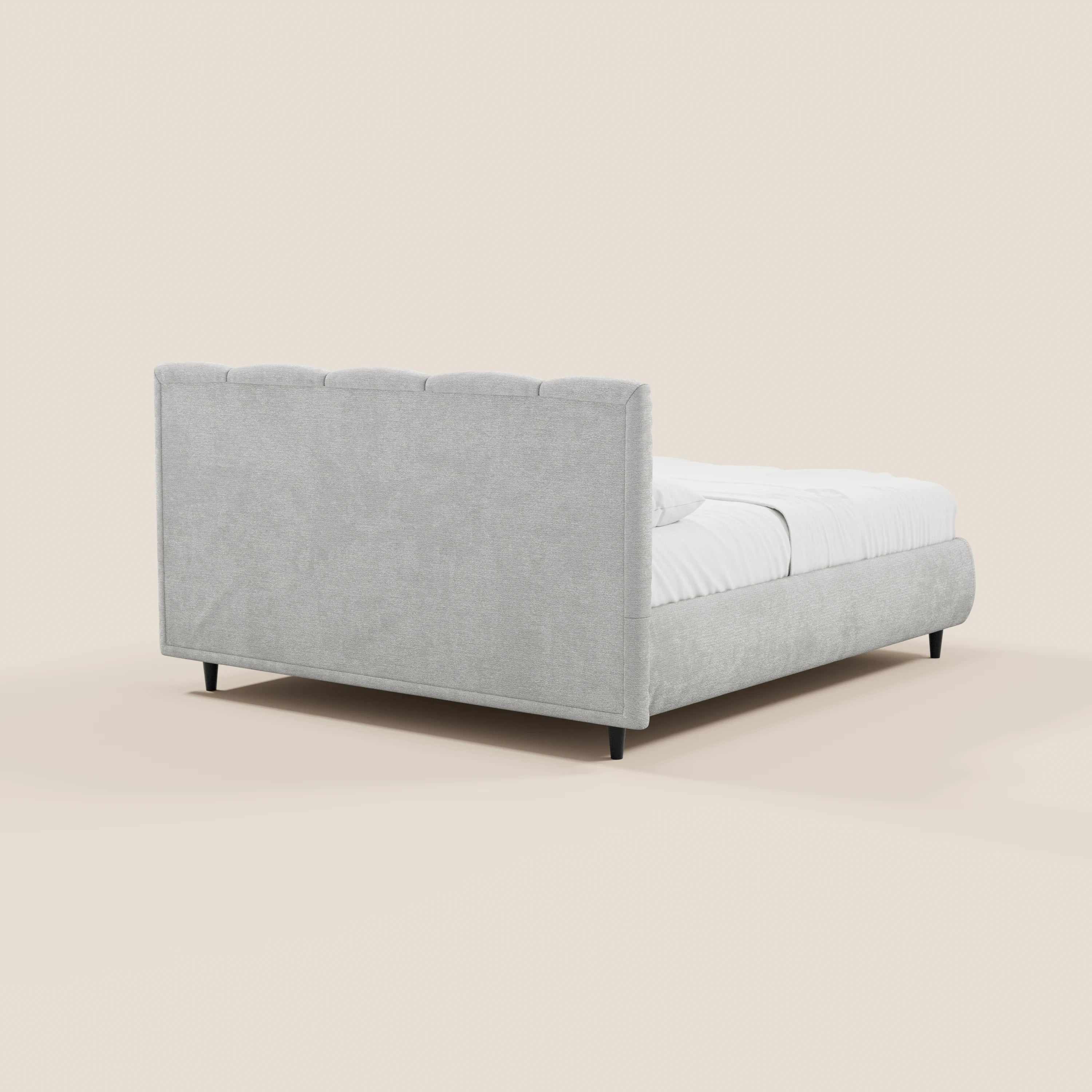 Il letto imbottito ARKAM di Letti.store, realizzato in tessuto Oeko-Tex®, presenta una testiera alta con lavorazione verticale e un vano contenitore. Design shabby chic in grigio chiaro, con base corta e gambe nere, rifinito con biancheria bianca su sfondo beige.