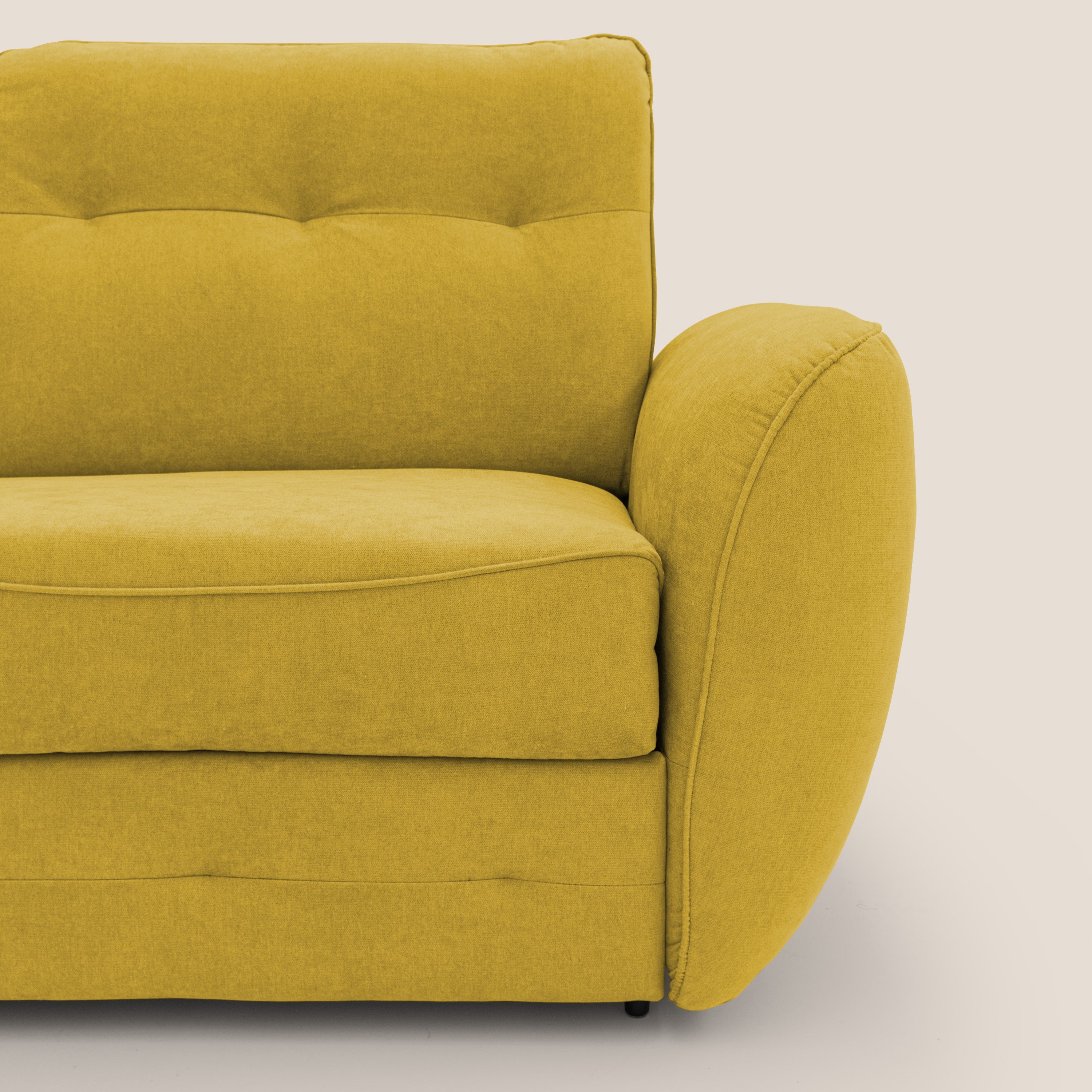 Primo piano del divano letto scandinavo Zeus con materasso H18 in tessuto impermeabile T02 giallo di Divani.Store, che mette in risalto lo schienale in peluche, il cuscino di seduta imbottito e il bracciolo arrotondato con cuciture a vista su uno sfondo beige chiaro.
