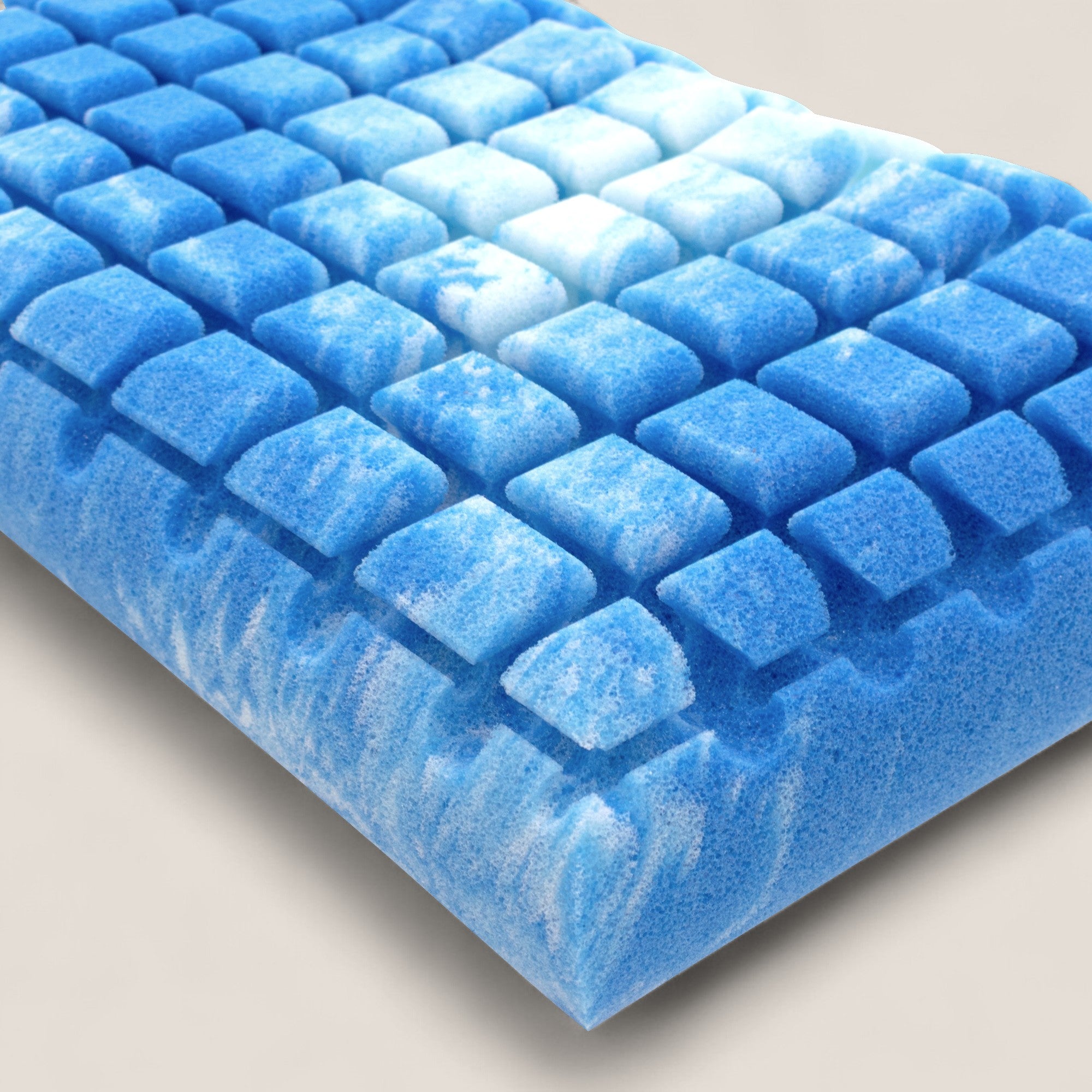 Un primo piano di AERION-BREEZE Guanciale in Memory Gel di Divani.Store mostra il suo cuscinetto in schiuma blu marmorizzata con una griglia di protuberanze in rilievo, che offre un rinfrescante supporto ergonomico e termoregolatore e mette in evidenza la sua texture e il suo design unici.