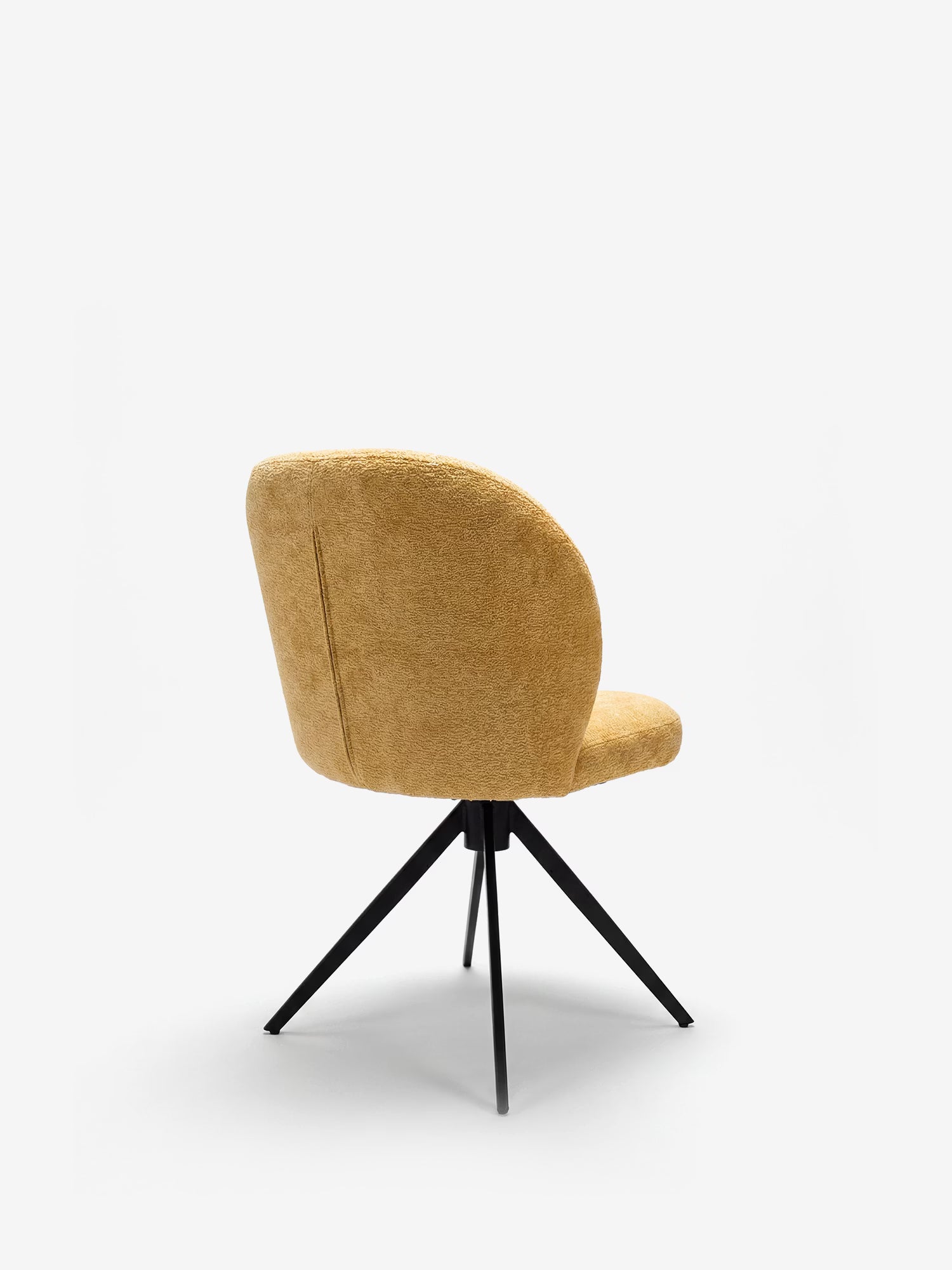 La sedia imbottita Alba di Divani.Store presenta un rivestimento curvo in tessuto effetto cotone OEKO-TEX® color senape e gambe in metallo nero divaricate verso l’esterno; nella foto è raffigurata vista da dietro su uno sfondo bianco a tinta unita.