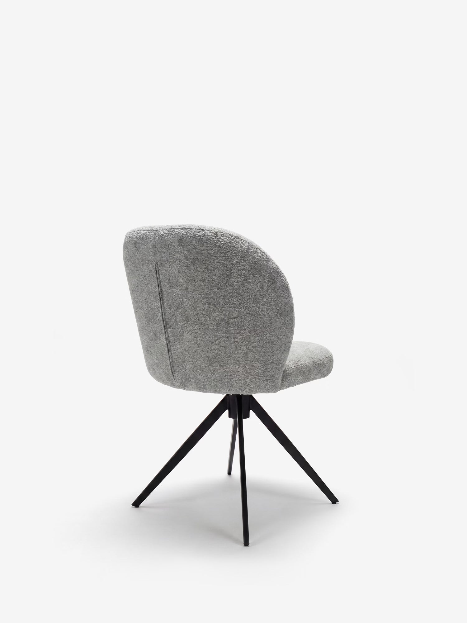 La sedia imbottita Alba di Divani.Store presenta schienale e seduta in tessuto effetto cotone OEKO-TEX® di colore grigio chiaro, dalle linee curve, sostenuti da gambe divaricate in metallo nero. Immagine ripresa da un’angolazione posteriore-laterale su uno sfondo bianco a tinta unita.