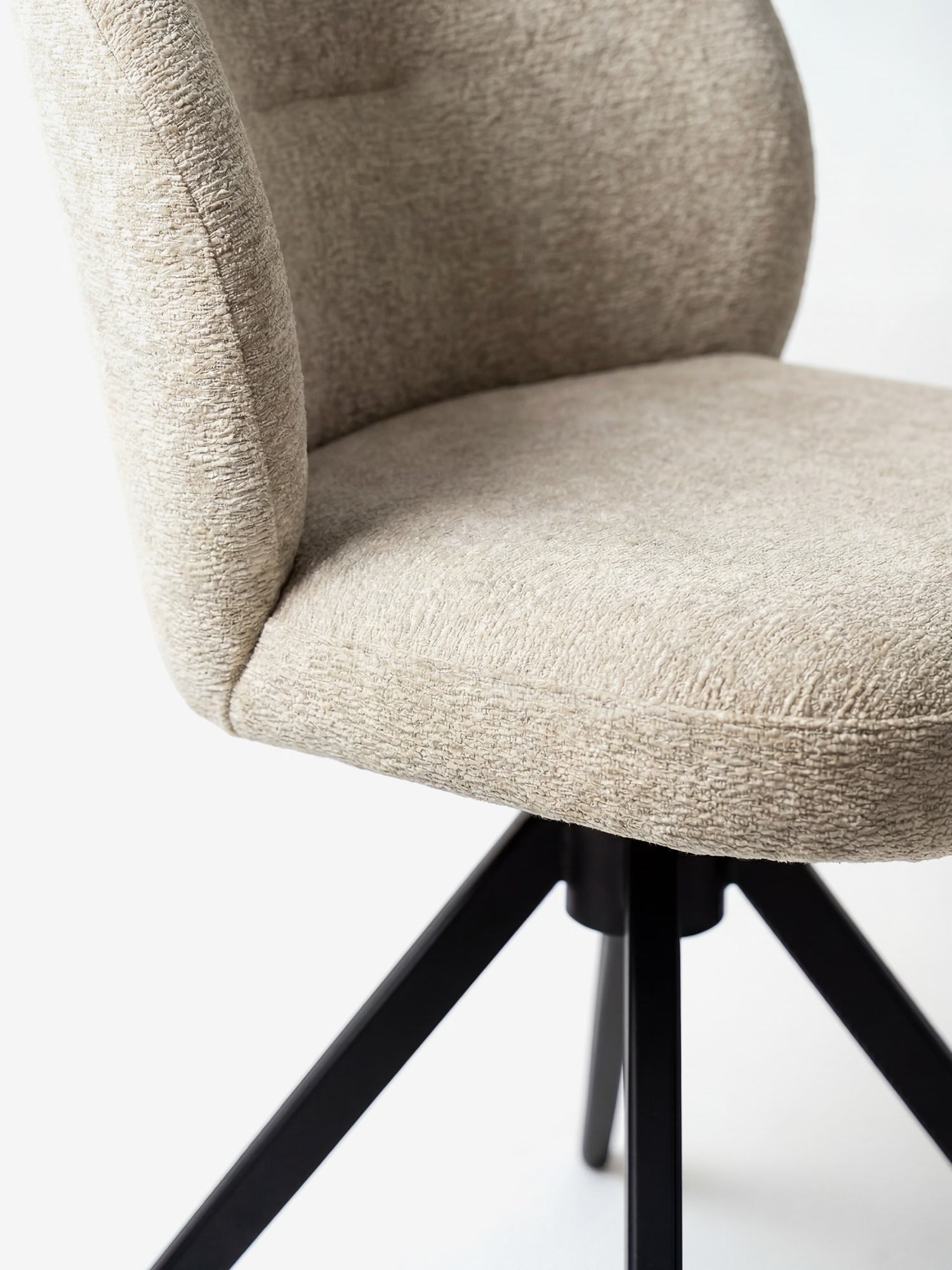 Un primo piano della sedia imbottita Alba di Divani.Store, rivestita in tessuto effetto cotone certificato OEKO-TEX®, con seduta e schienale imbottiti, caratterizzata da un'elegante base in metallo nero, su sfondo bianco.