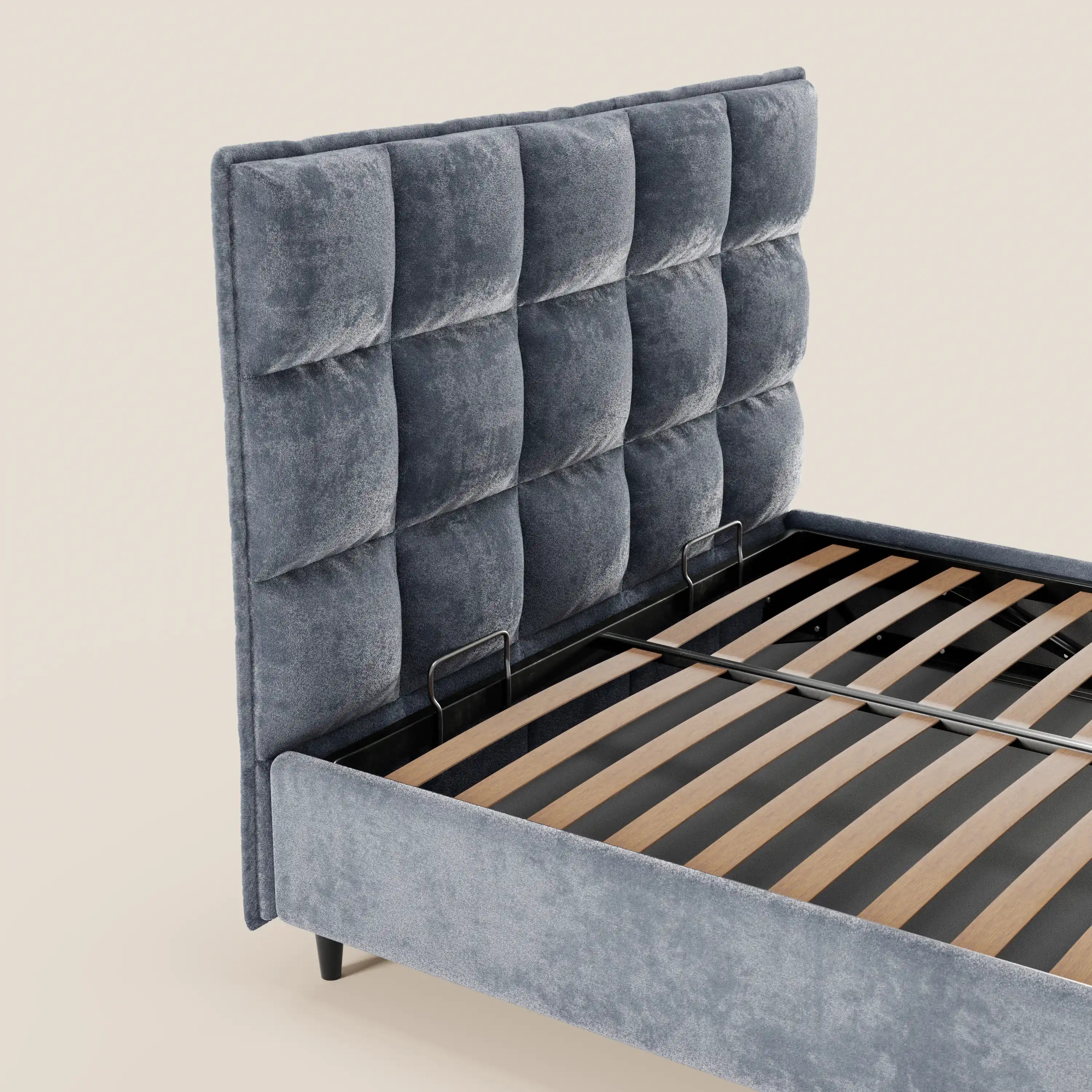 Il letto imbottito AURO di Letti.store è caratterizzato da un'alta testiera capitonné in ciniglia certificata Oeko-Tex®, doghe in legno, una barra centrale in metallo nero e un vano contenitore. Materasso non incluso. Lo sfondo è beige chiaro.