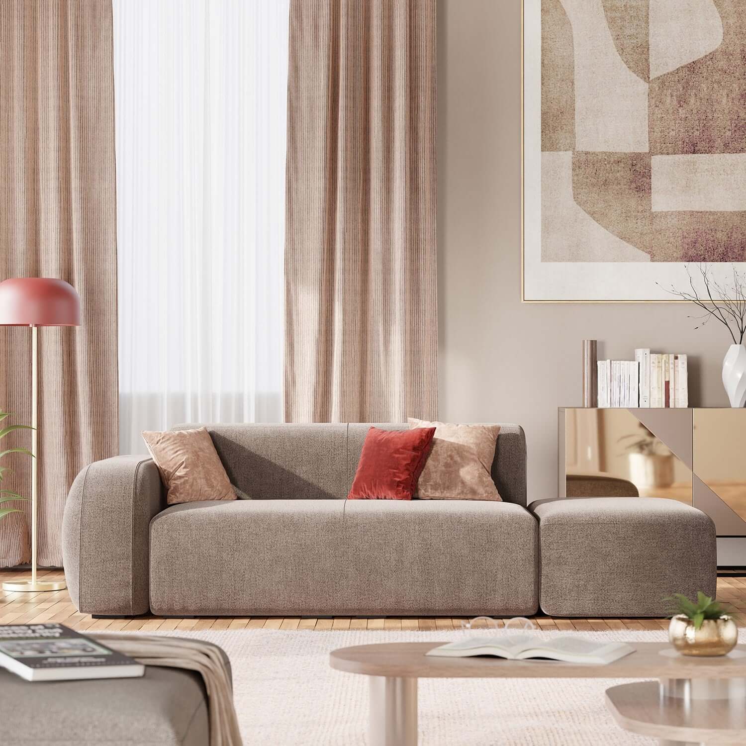 Un soggiorno moderno con il BonBon Divano componibile di Divani.Store in tessuto talpa T23, due cuscini beige e uno rosso, tende alte beige, grandi opere d'arte astratta, un tavolino rotondo con libri e una credenza dorata con decorazioni.
