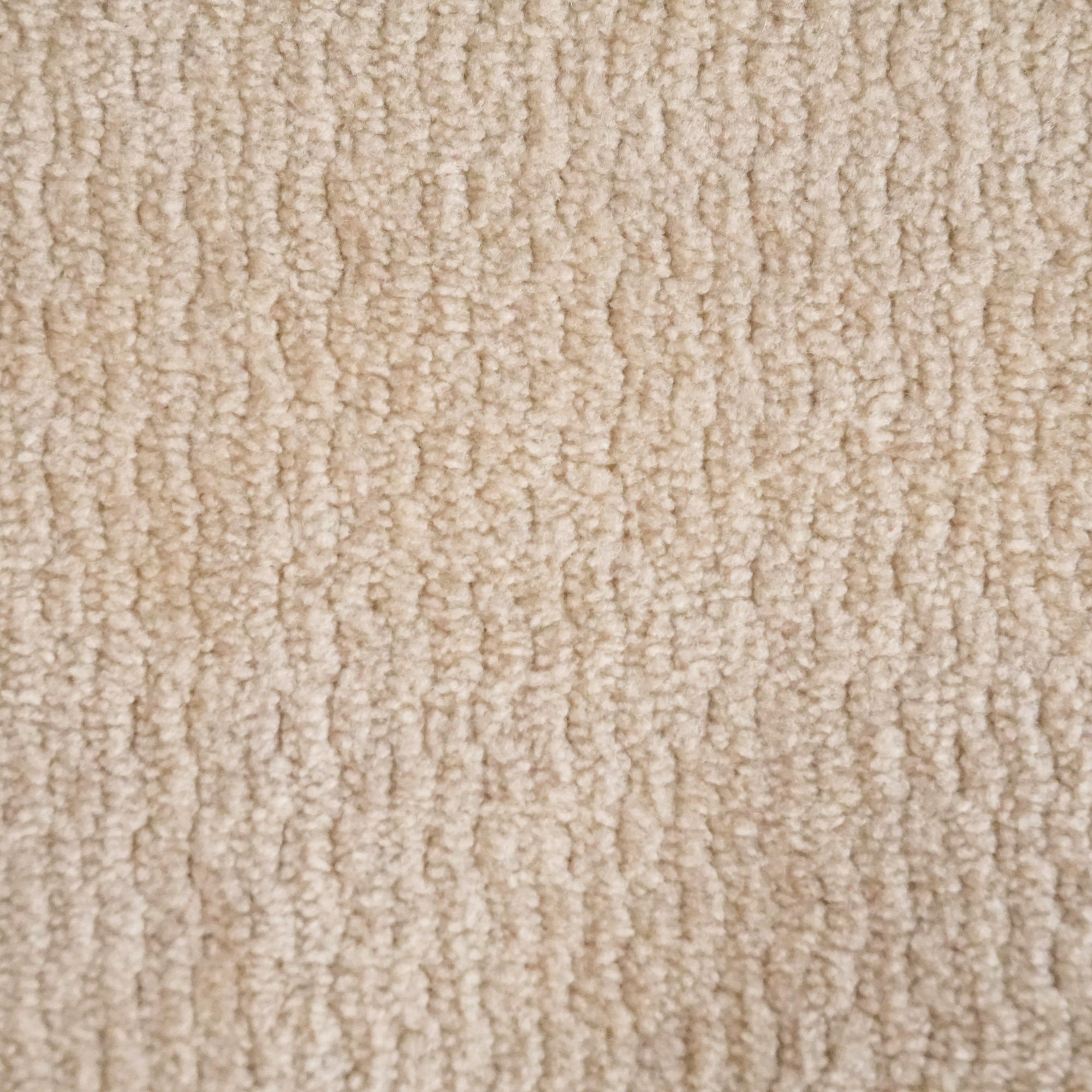 Primo piano di Personalizzazione in T32 di Divani.Store: un tappeto beige con un soffice e fitto vello a forma di anello e una texture leggermente ondulata. Le ombre sottili evidenziano le anse in rilievo, creando uno sfondo uniforme e neutro.