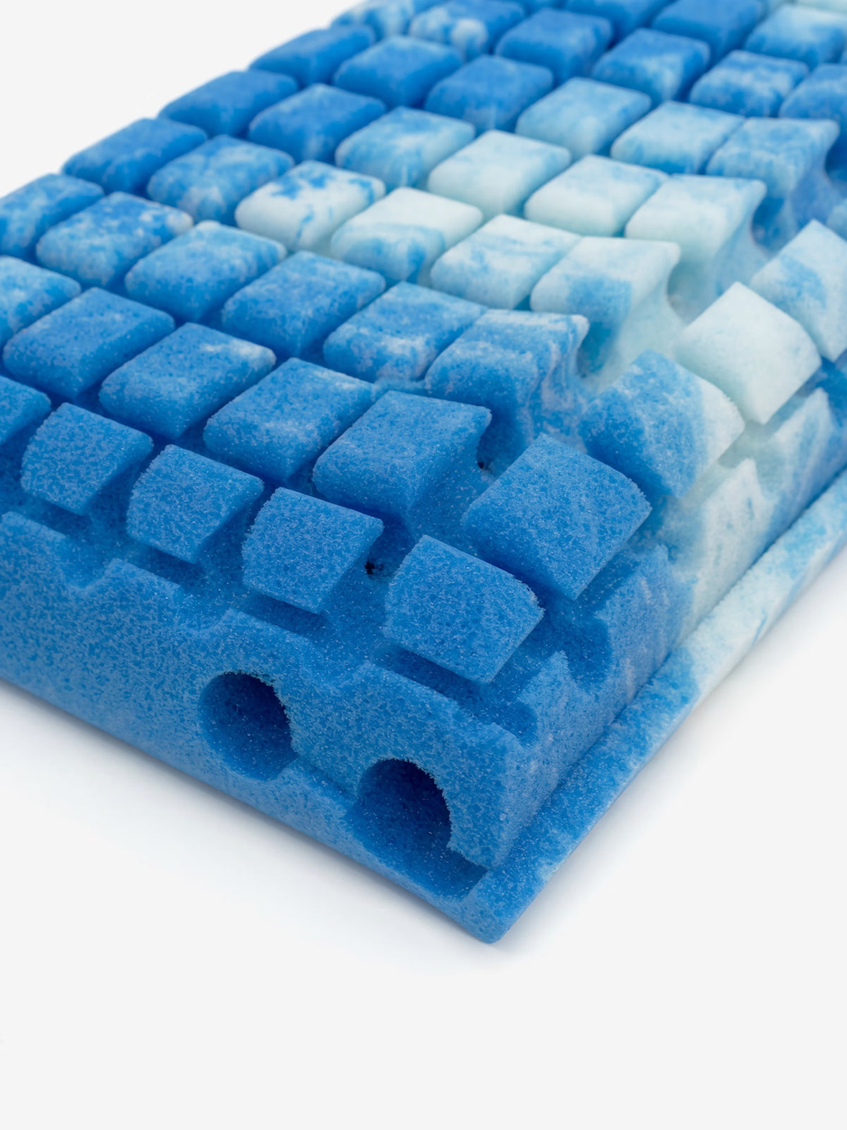 Primo piano del prodotto Divani.Store AERION-BREEZE – Guanciale in Memory Gel rinfrescante e termoregolatore, caratterizzato da un cuscino in schiuma con sfumatura blu e bianca, dotato di una griglia di segmenti quadrati in rilievo e due fori rotondi visibili sul bordo sinistro. La consistenza morbida e flessibile è progettata ergonomicamente per garantire un sostegno cervicale ottimale e un comfort superiore, grazie all’innovativa tecnologia Polygel.
