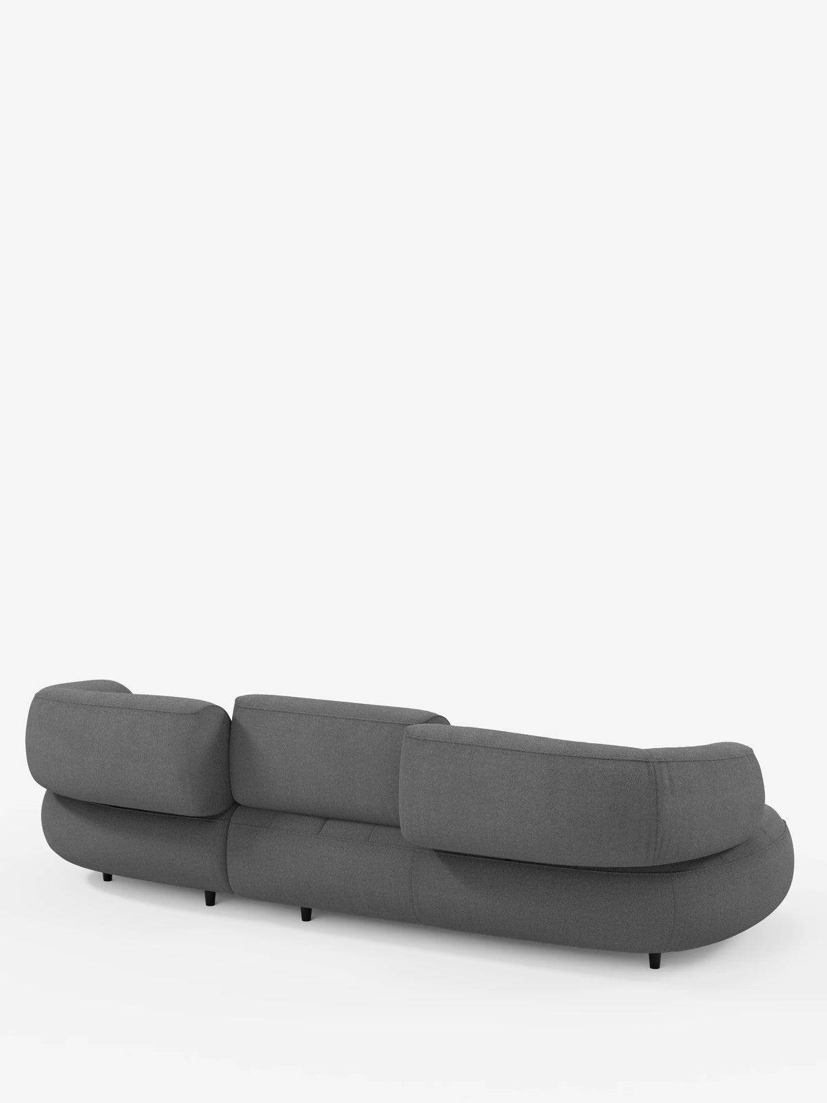 Un divano angolare Croissant grigio scuro dal design a fagiolo e con schienali scorrevoli, rivestito in morbido tessuto effetto cotone lavabile T33; nella foto è raffigurato di retro con tre schienali imbottiti e gambe cilindriche basse di colore nero su sfondo bianco.