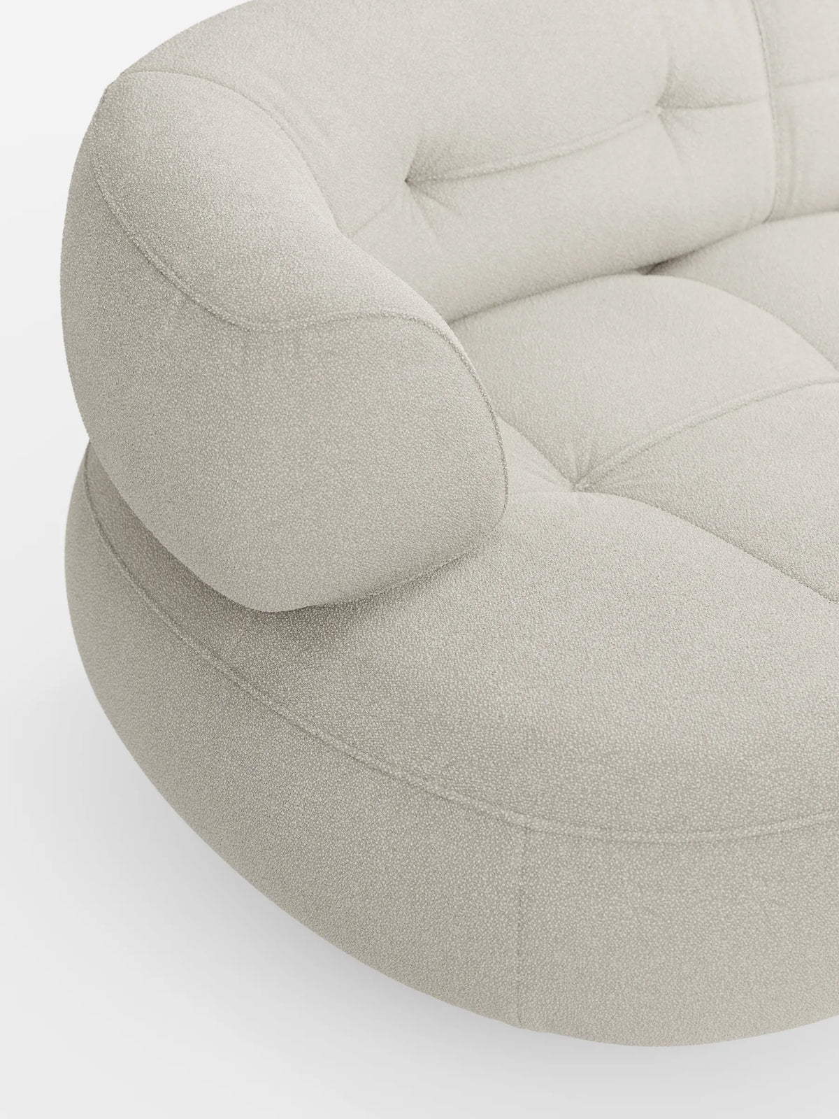 Un divano angolare Croissant dalle linee curve, color beige, con design a forma di fagiolo e schienali scorrevoli, rivestito in morbido tessuto effetto cotone smacchiabile T33, caratterizzato da un design arrotondato e organico, tessuto testurizzato, delicati dettagli trapuntati e un aspetto soffice.