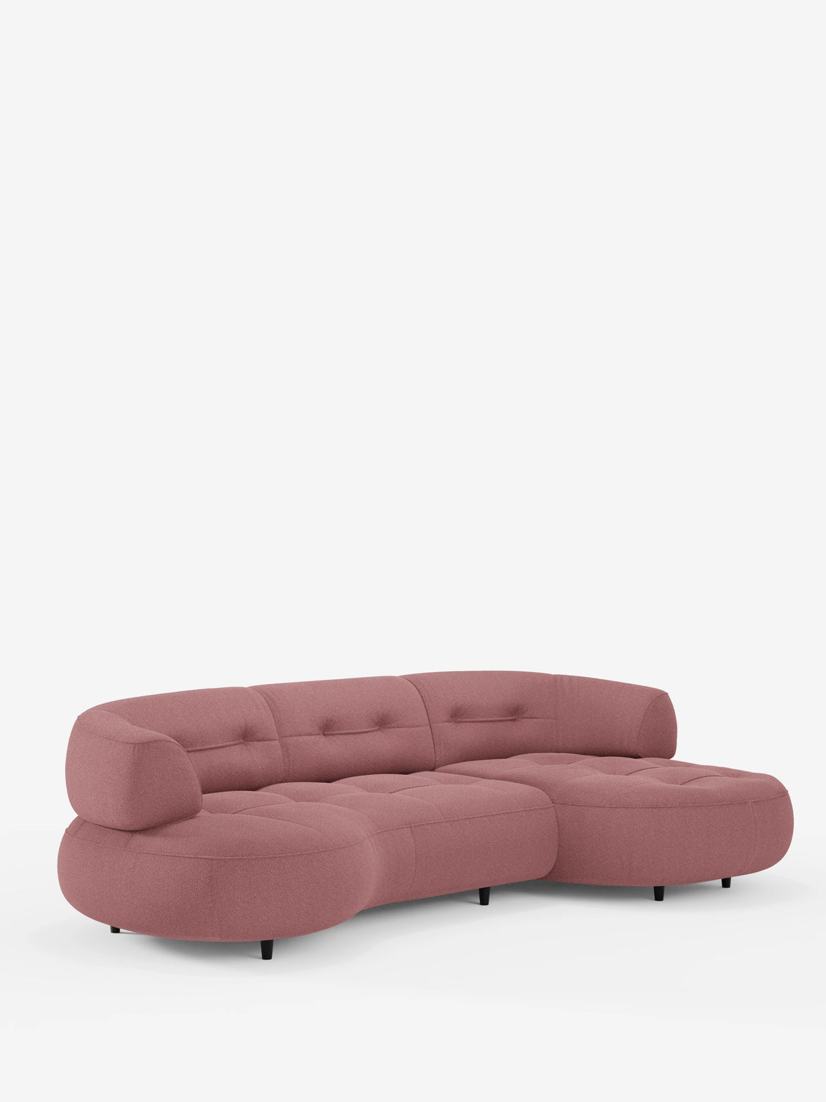 Un divano angolare Croissant dalla forma ricurva a fagiolo, con schienali scorrevoli in morbido tessuto effetto cotone smacchiabile T33 color rosa polveroso, caratterizzato da una seduta trapuntata su gambe cilindriche basse di colore nero su sfondo bianco.