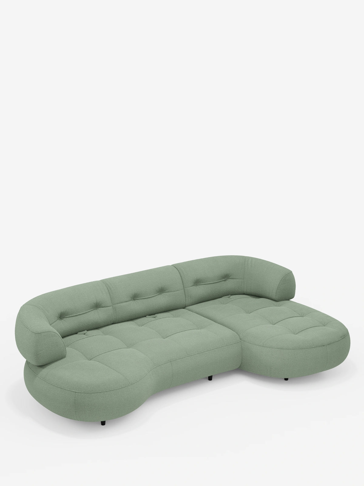 Un divano angolare Croissant color verde salvia, dal design a forma di fagiolo e con schienali scorrevoli in morbido tessuto effetto cotone smacchiabile T33, caratterizzato da una forma curva a fagiolo, tessuto trapuntato e schienali bassi su gambe corte e scure.