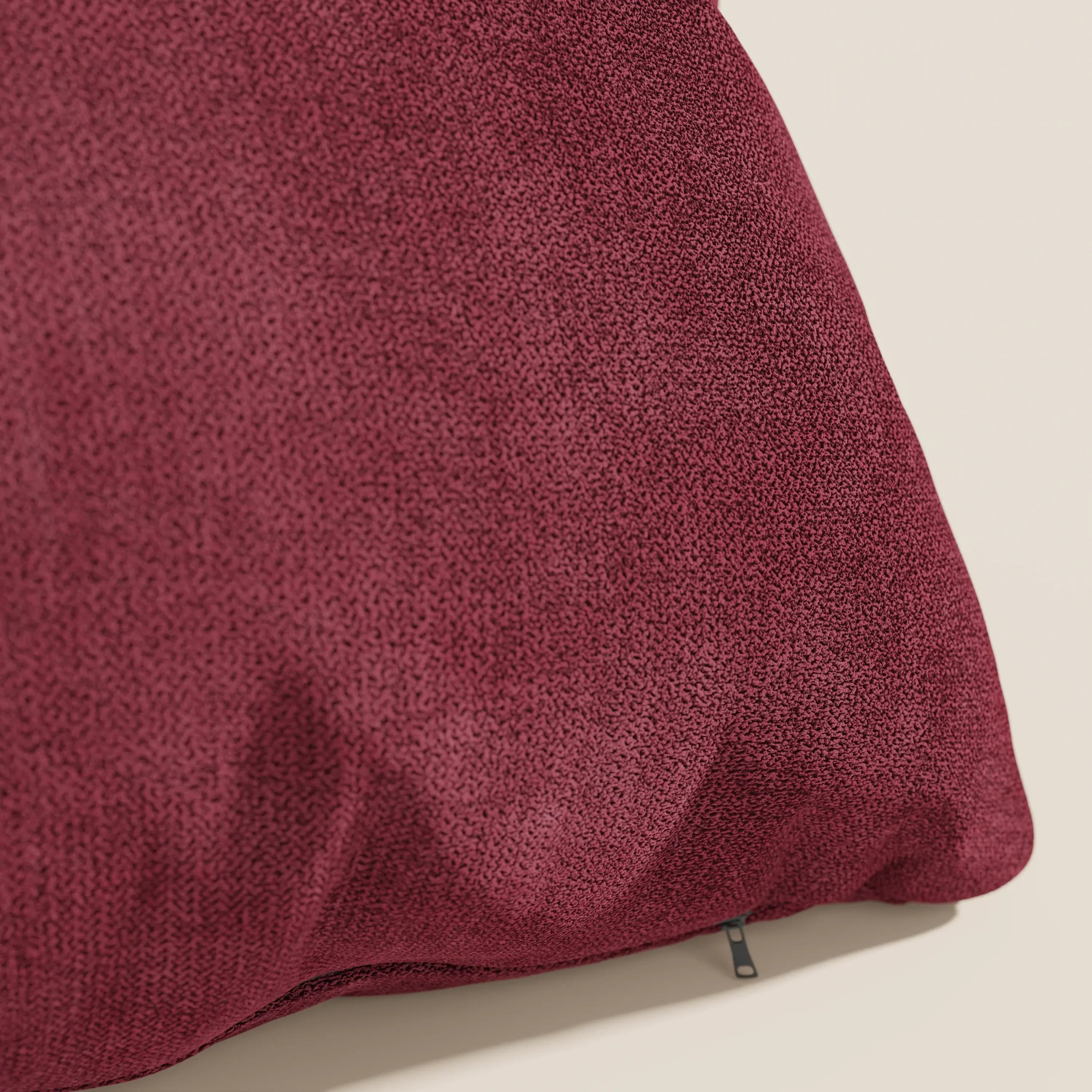 Un primo piano del cuscino Destiny di Divani.Store in T02 rosso mostra il suo tessuto morbido, strutturato e impermeabile e la cerniera inferiore. Elegante e di facile manutenzione, questo cuscino decorativo è caratterizzato da una trama fine e da un rivestimento sfoderabile e lavabile.