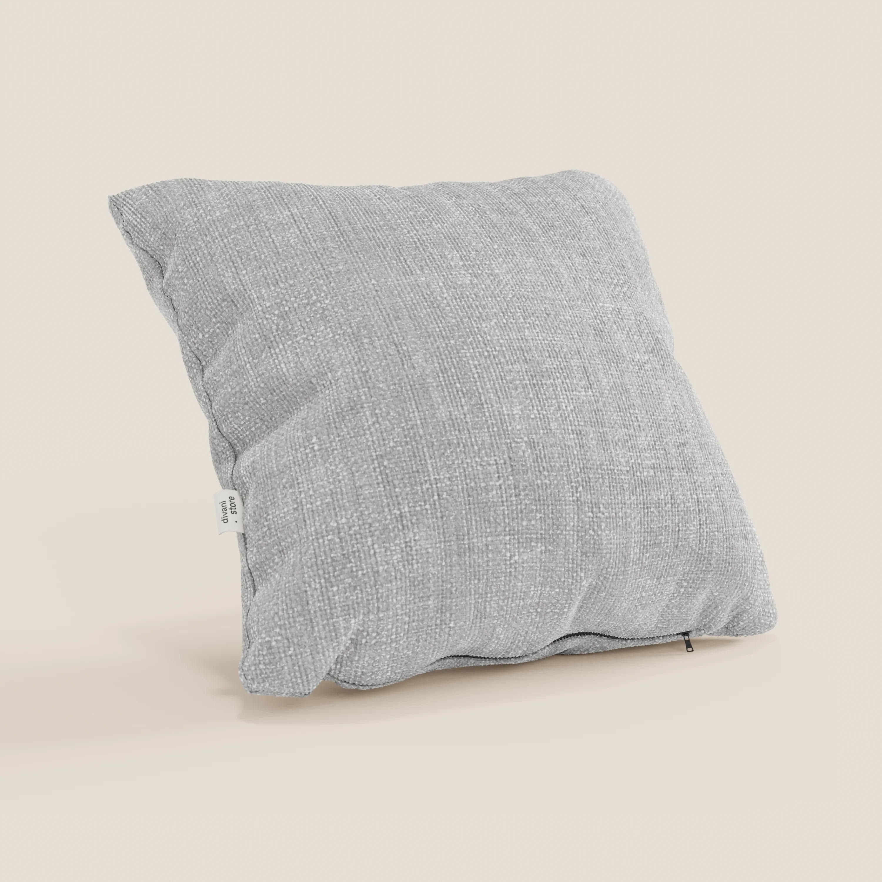Il cuscino Lyon di Divani.Store, 45x45 cm in T06 grigio, è caratterizzato da un tessuto morbido intrecciato impermeabile e da un coperchio testurizzato. Si trova su una superficie beige chiaro con etichetta laterale bianca e cerniera a vista in una scena minimalista.