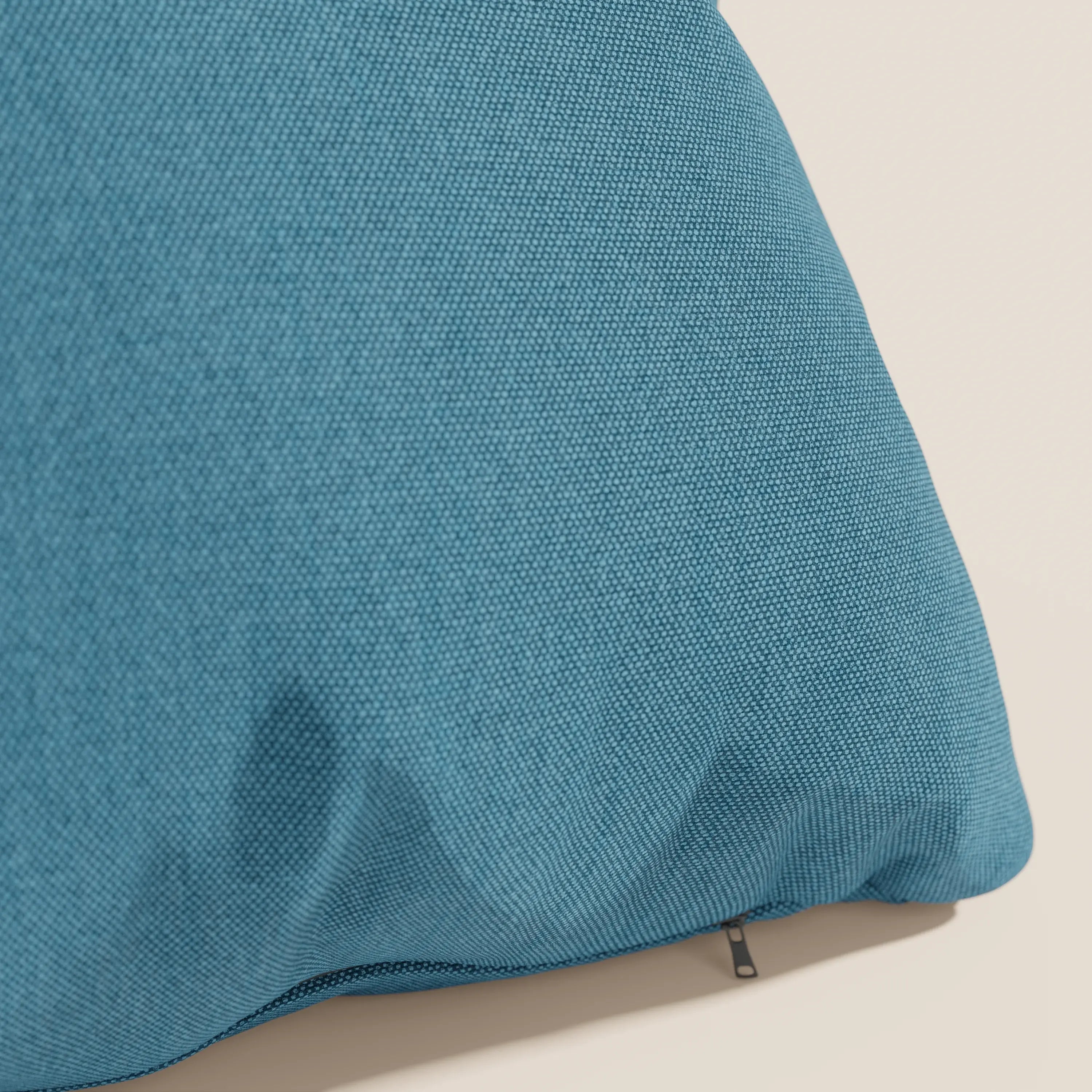 Primo piano del cuscino Honey 45x45 di Divani.Store in tessuto simil cotone impermeabile T13 azzurro, angolato su uno sfondo beige chiaro. La cerniera parzialmente visibile della fodera lavabile ne rivela la trama fine e leggermente rugosa.