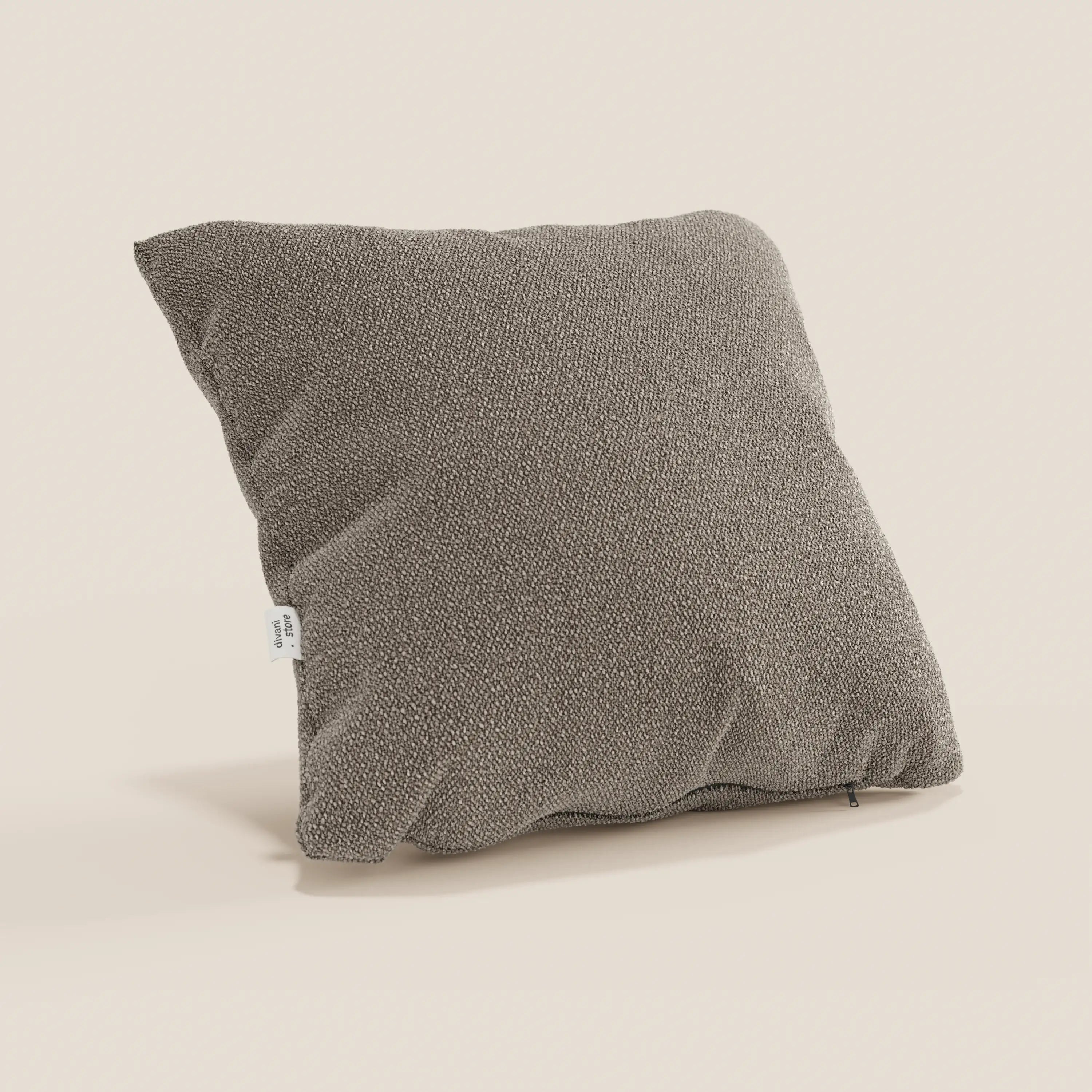 Il cuscino Lambada di Divani.Store, presentato in grigio-marrone con etichetta laterale bianca a vista, è caratterizzato da un tessuto naturale, antimacchia e impermeabile. Di forma quadrata e strutturata, è esposto su uno sfondo chiaro con un aspetto morbido e angolato e una sottile ombra.
